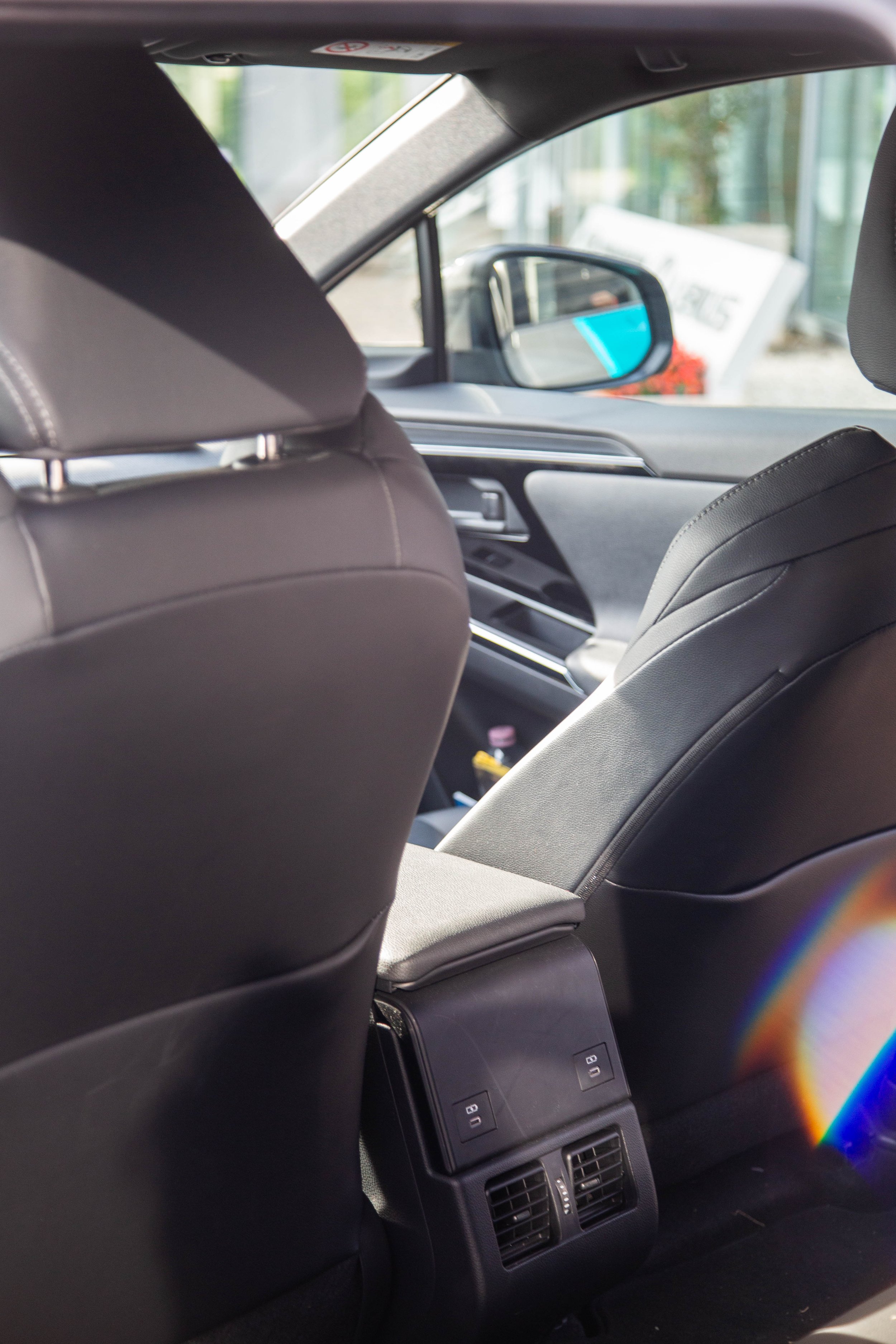 Interior of a modern car showing front seats, dashboard, and side mirror, with sunlight entering through the windows.