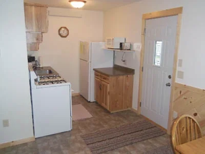Kitchen with white refrigerator, stove, microwave, wooden cabinets, and a dining table with chairs.