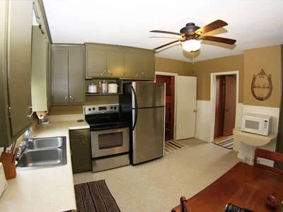 Kitchen with gray cabinets, stainless steel refrigerator, stove, microwave, and a small dining table.