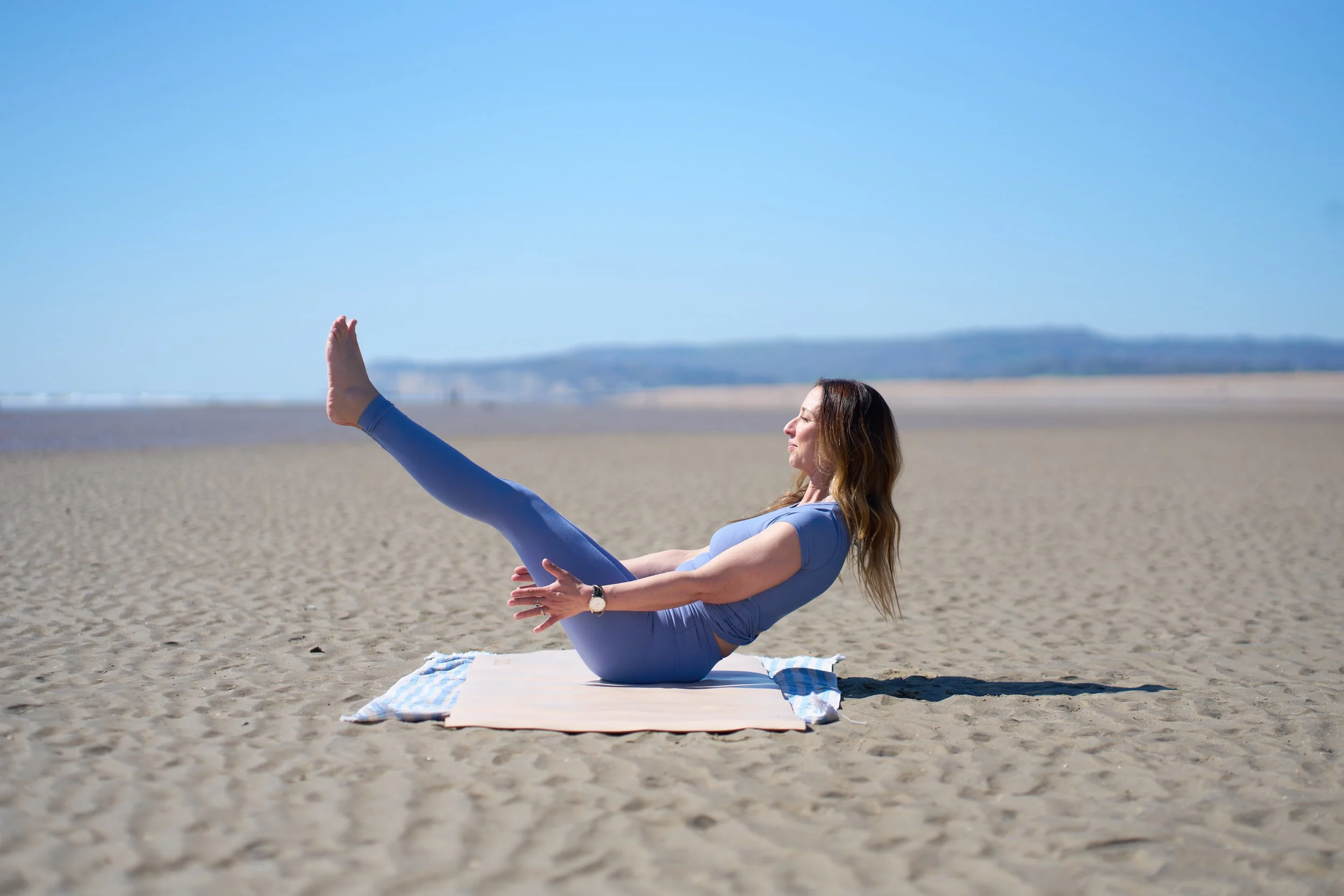 A rolled white yoga mat standing upright on a textured mat, casting a shadow on a beige background.