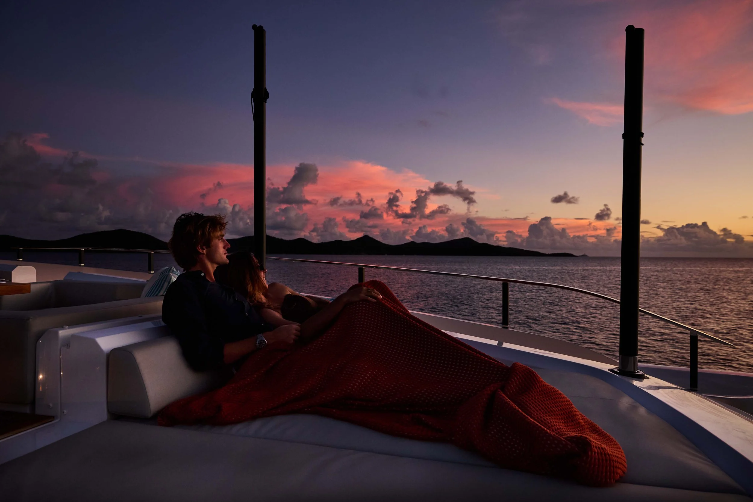 Couple relaxing under a blanket on the upper deck of a luxury yacht