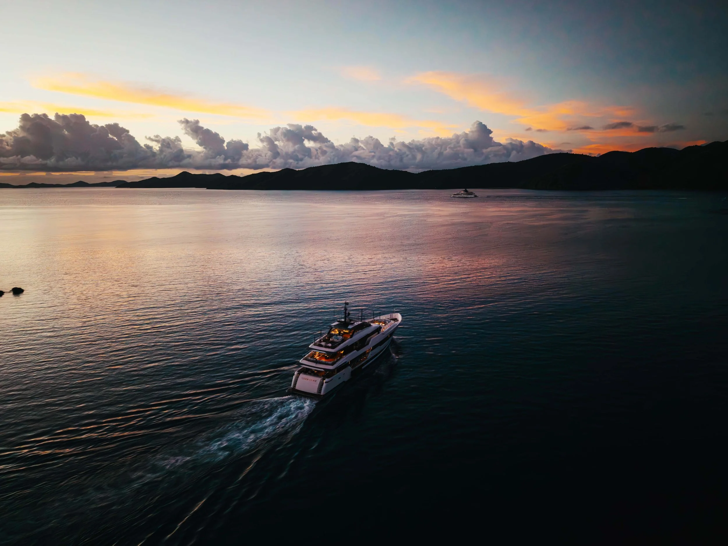 Drone view of a luxury yacht at sunset on calm ocean water
