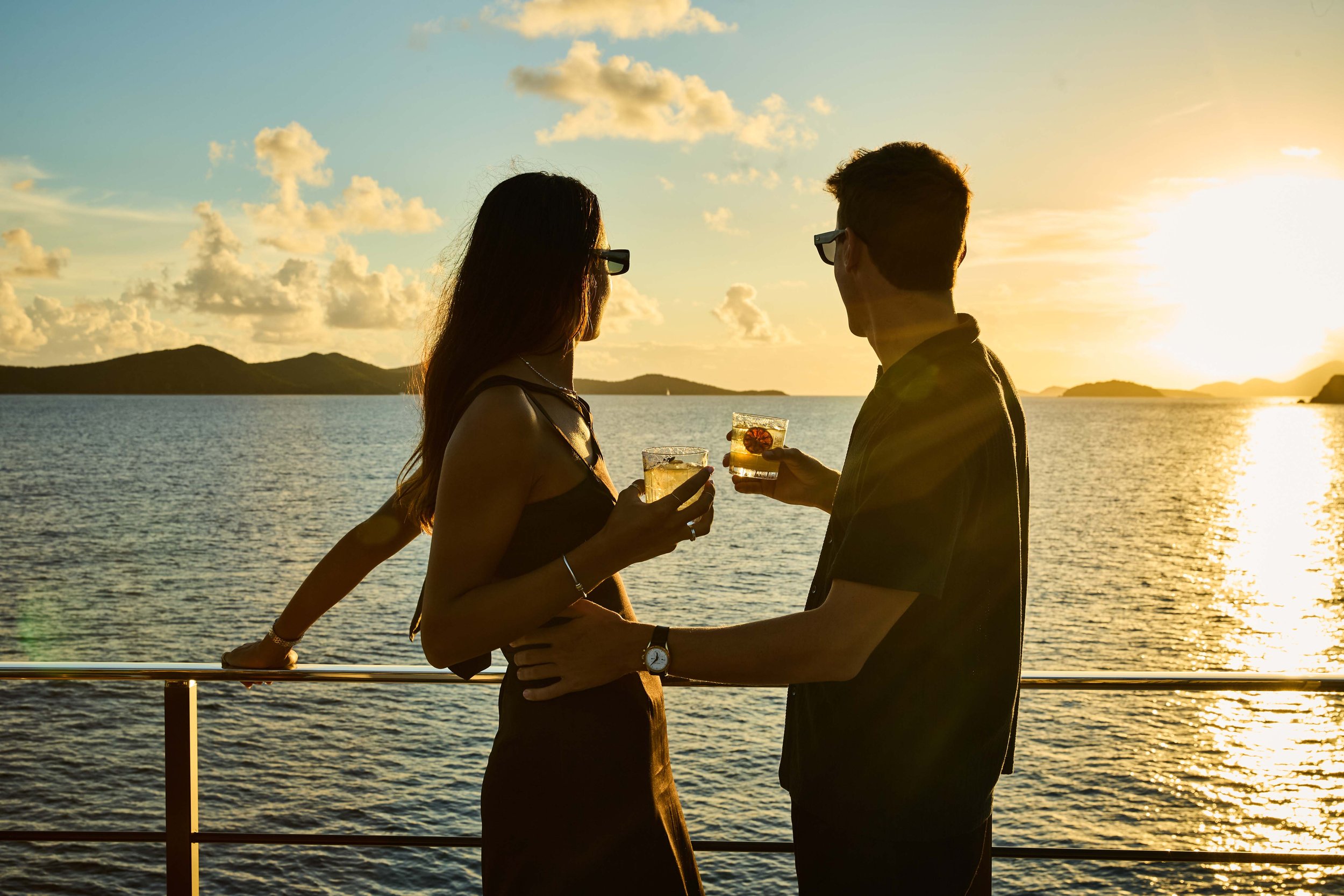 Couple enjoying cocktails at sunset onboard a luxury yacht