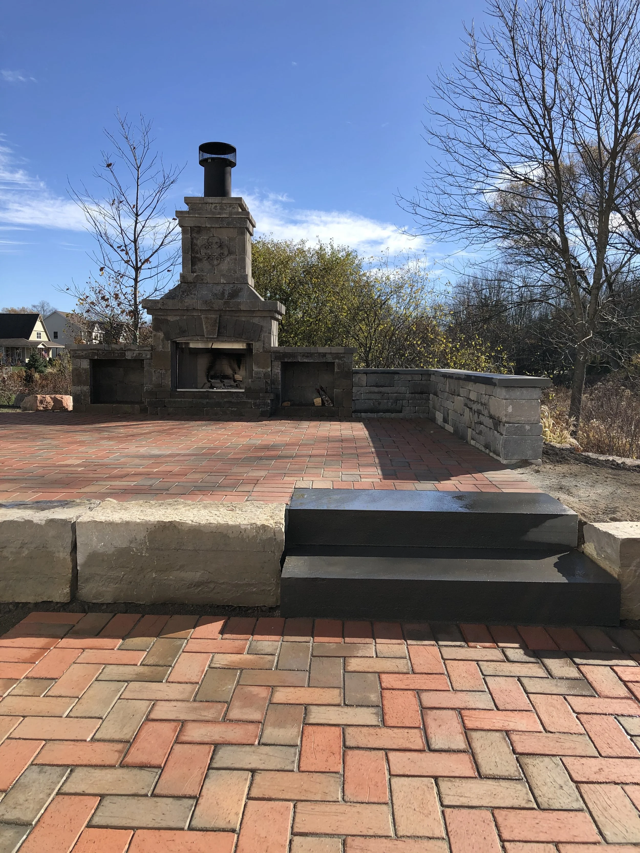 Outdoor brick patio with brick and stone fireplace.