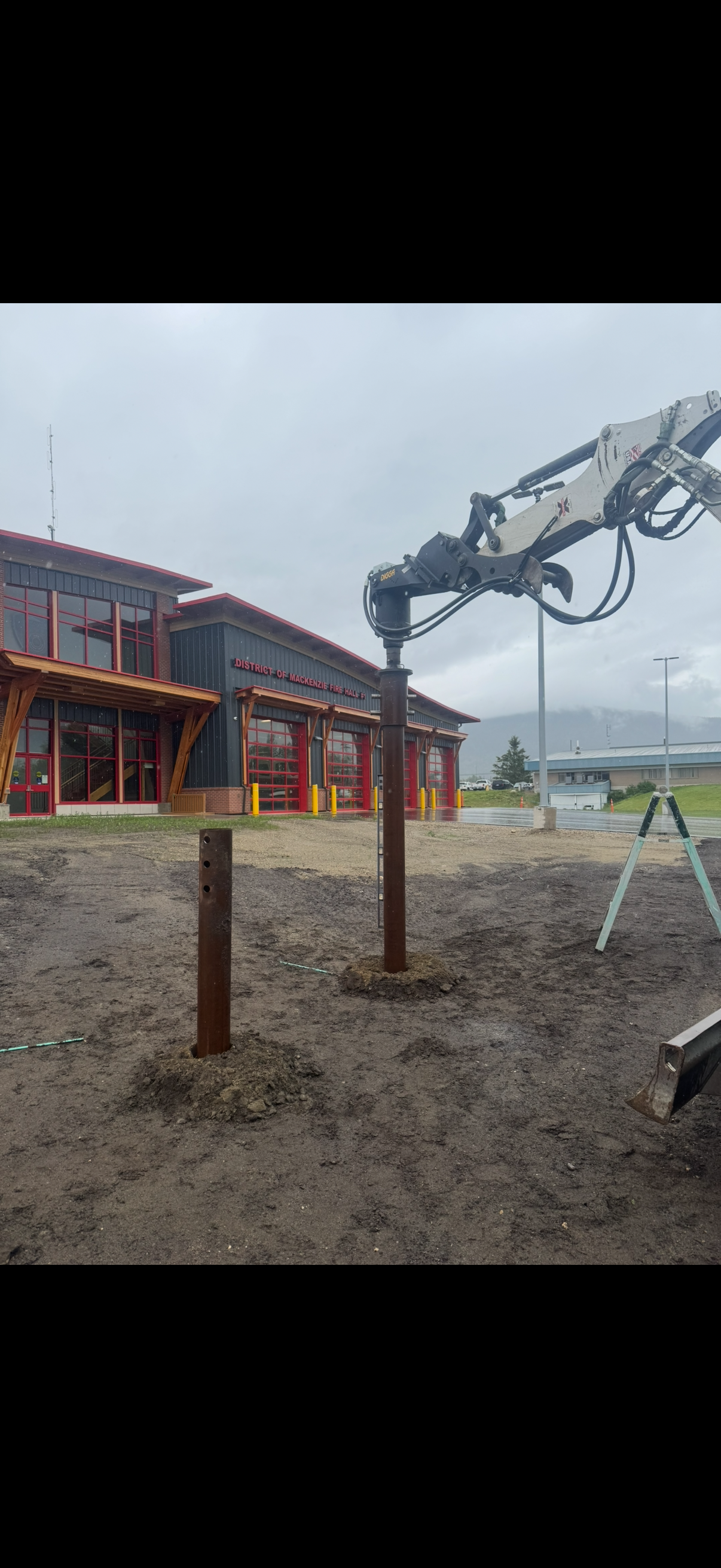 Construction site in front of the District of Mackenzie Fire Hall with a large excavator removing soil and preparing the ground.