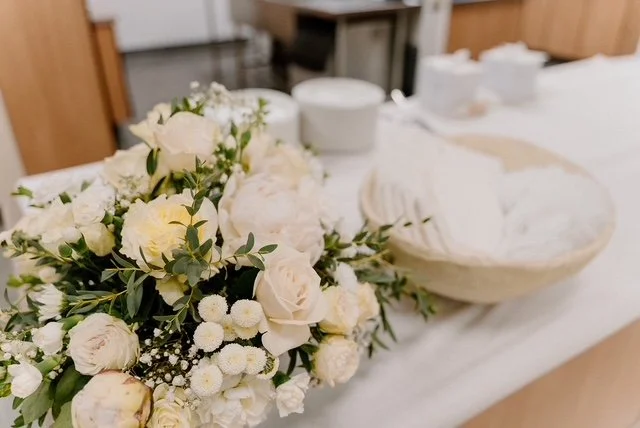 A bouquet of white and pale yellow flowers on a white table.