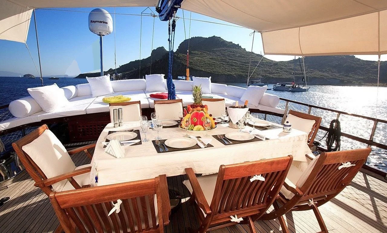 Outdoor gulet dining area overlooking a Bodrum harbor.