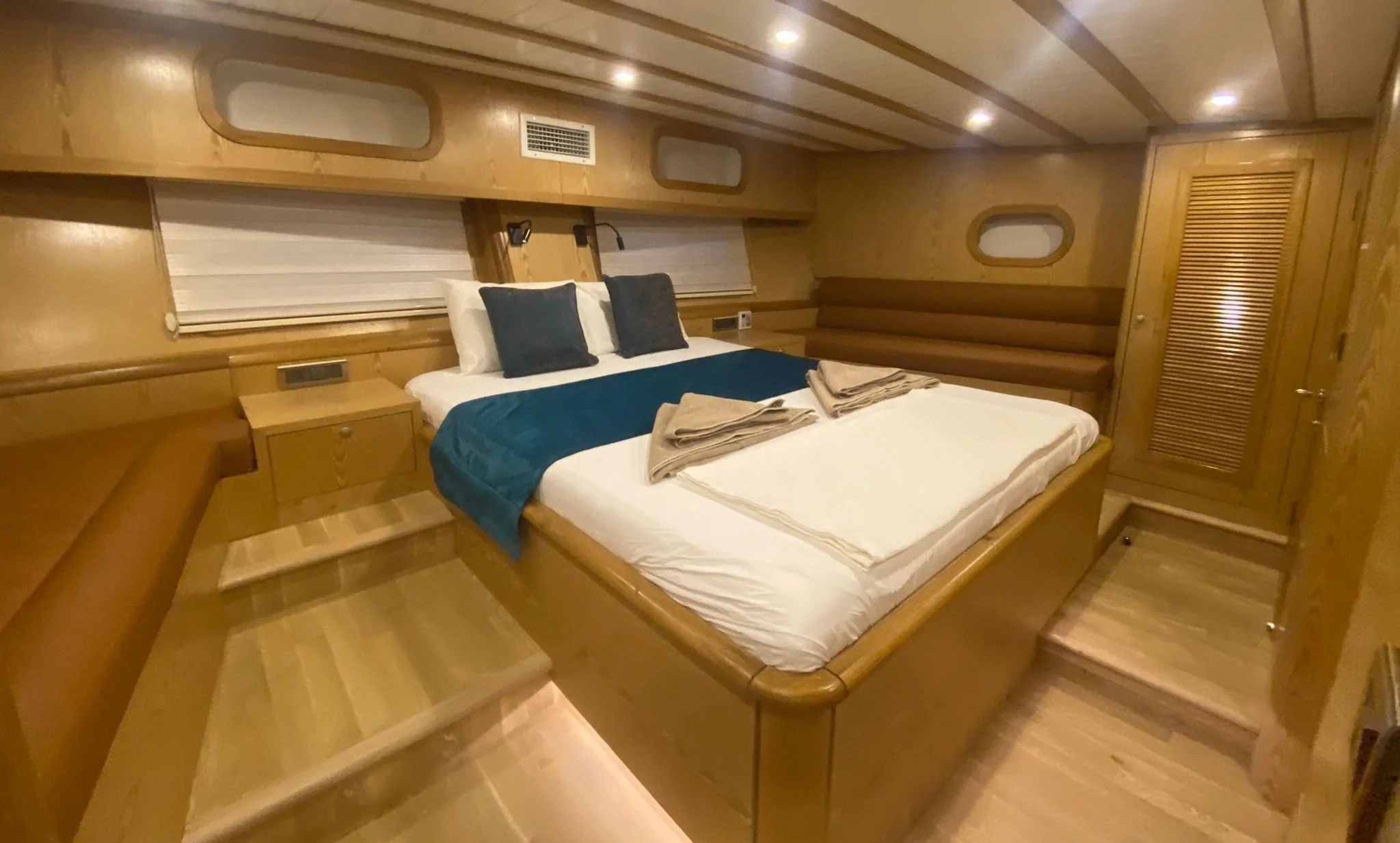 Private gulet bedroom with wooden interior and teal bedding