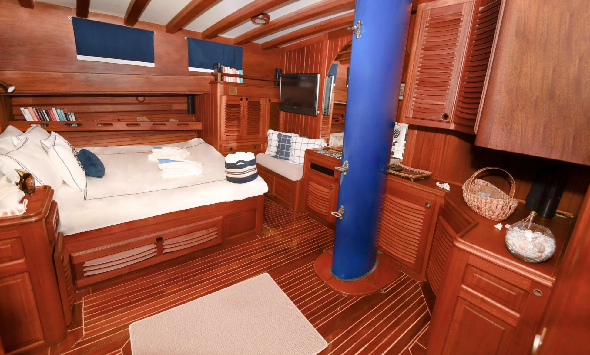 Private gulet bedroom with warm wooden walls and blue details.