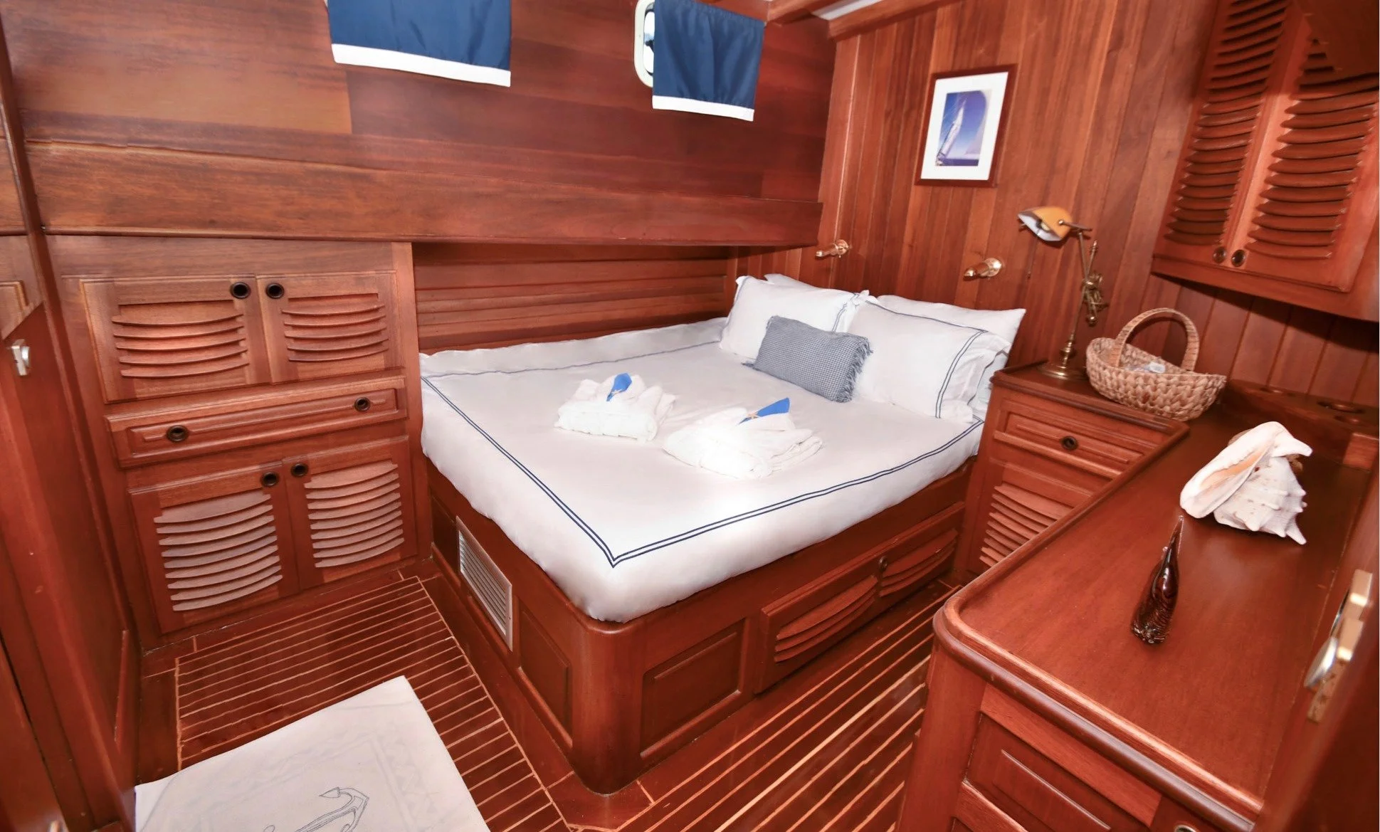 Private gulet bedroom with wooden interior and white bedding.
