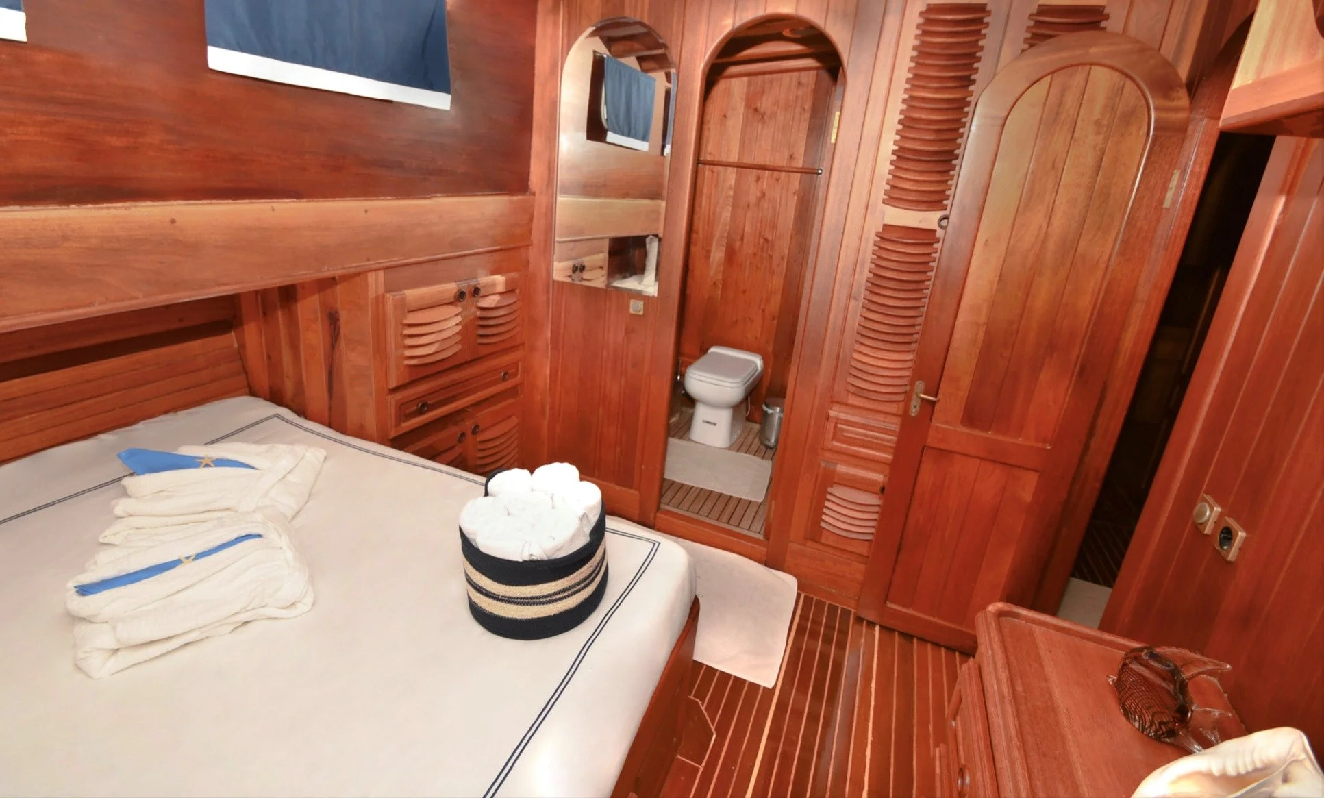 Wooden gulet cabin bedroom with bathroom access.