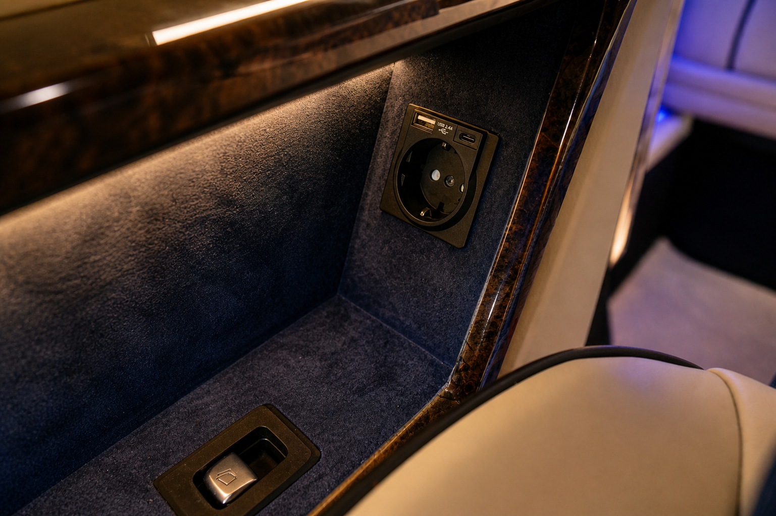 Power outlet with USB port on a dark blue surface in an airplane or train cabin.