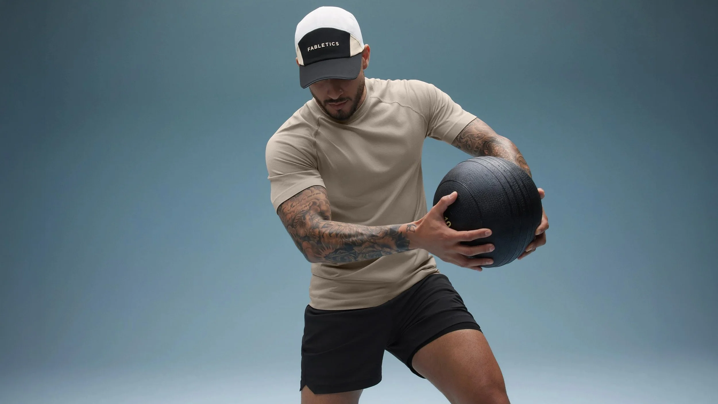 Art director on-figure e-commerce shoot, Los Angeles. A man wearing a beige T-shirt, black shorts, and a baseball cap with