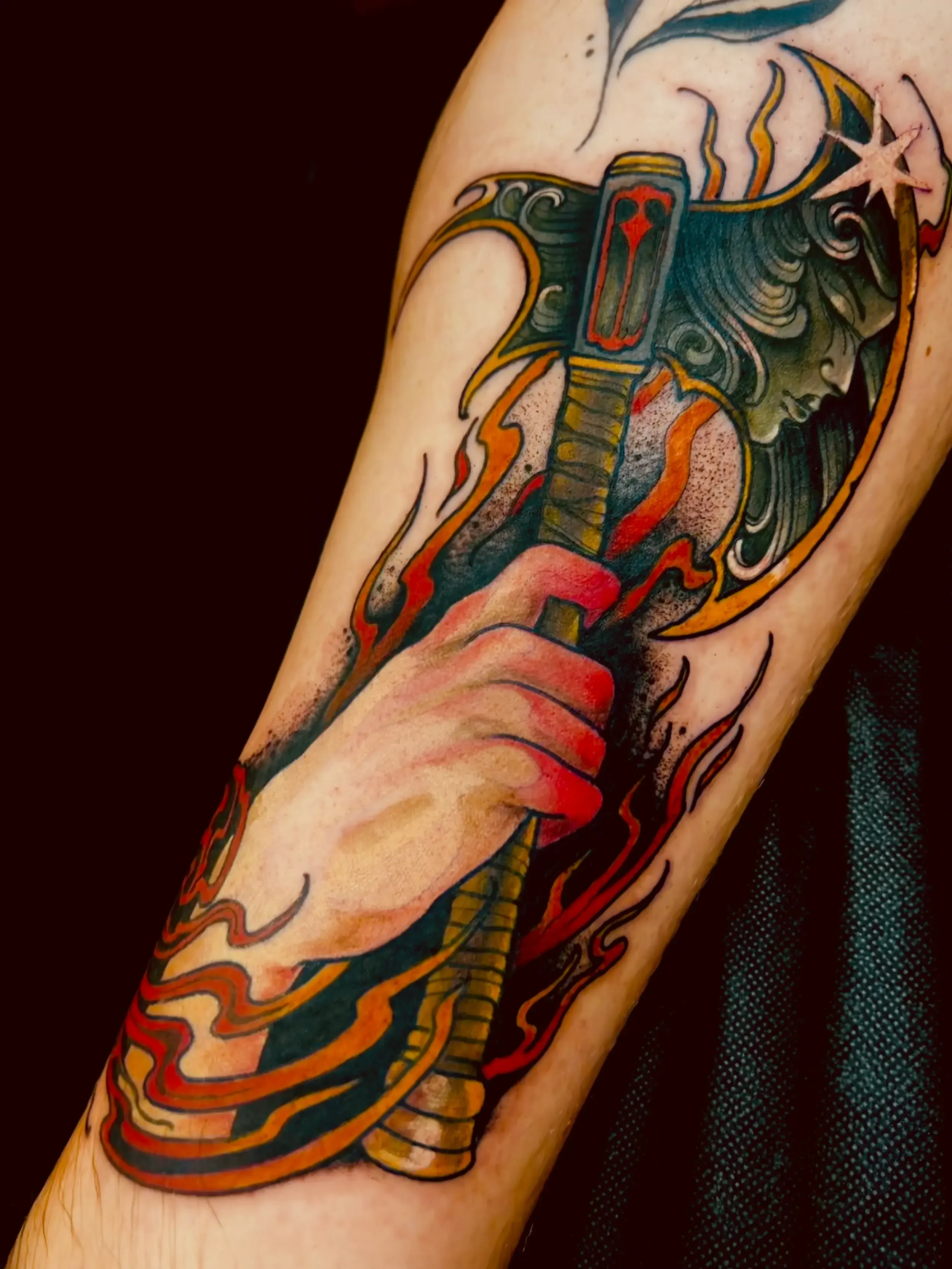Colorful illustrative tattoo of a hand holding a fantasy axe. Done by female tattoo artist Dana Carlson in Virginia.