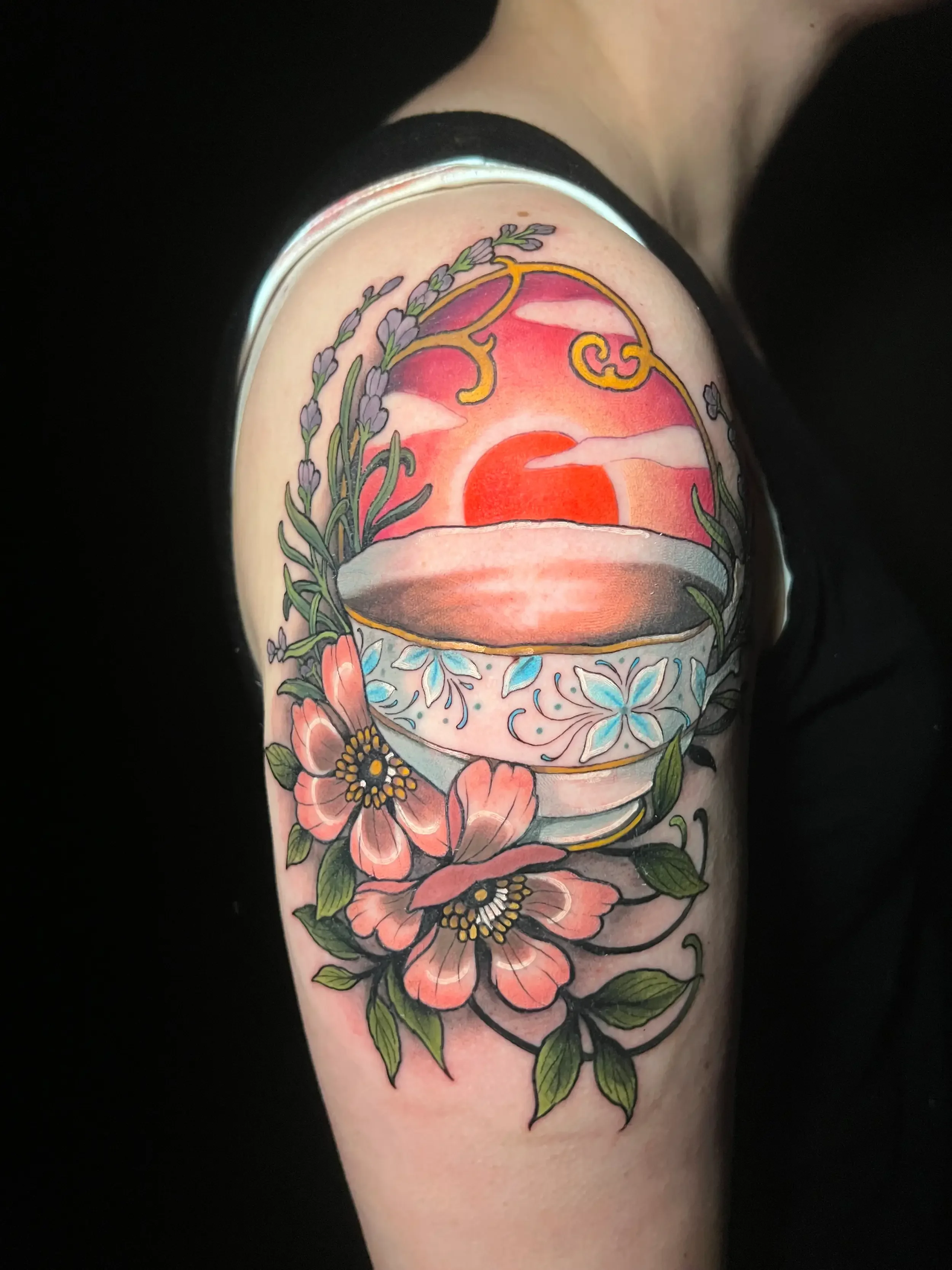 Colorful tattoo of a sunset surrounded by pink flowers and lavender, on a person's upper arm. Done by female tattoo artist Dana Carlson in Virginia.