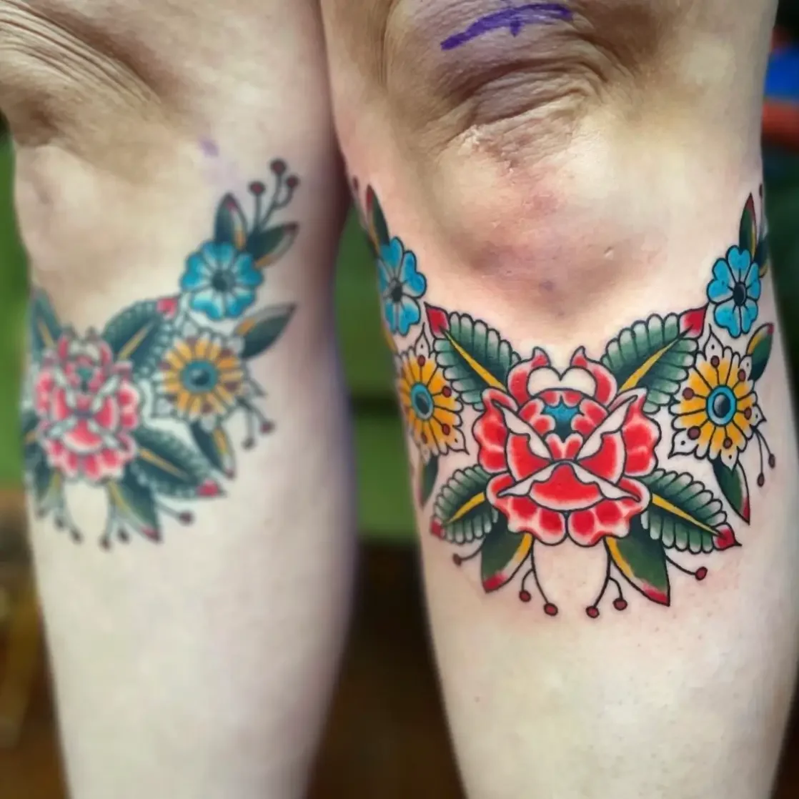 Colorful American trad style floral tattoos on thighs with a prominent red flower and green leaves, showing details and vibrant colors. Custom design by Jess, tattoo artist in Richmond, Virginia.