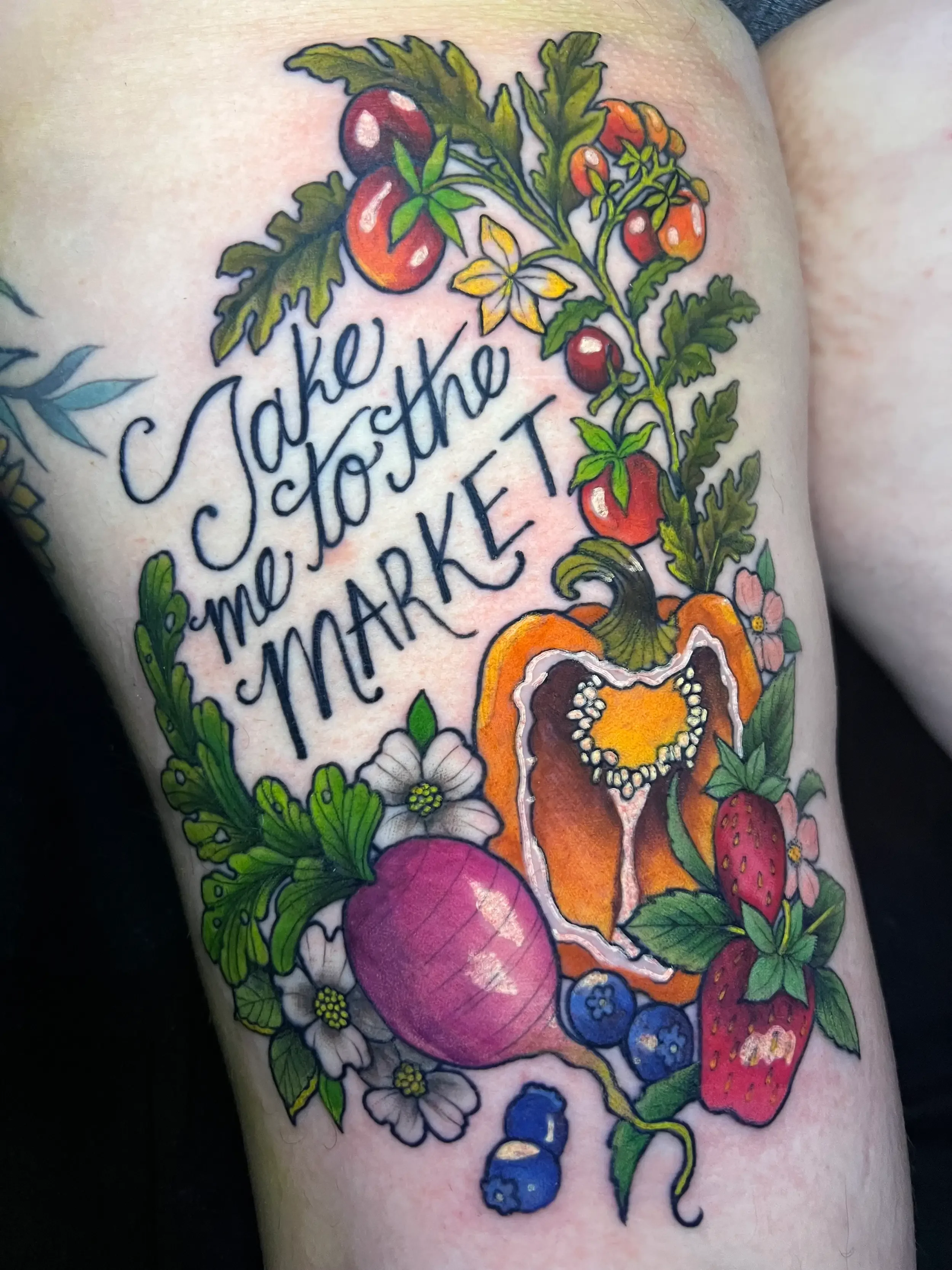 Custom color tattoo featuring the phrase 'Take me to the market' in script font surrounded by various fruits and vegetables, including tomatoes, strawberries, blueberries, a radish, and strawberries. Done by female tattoo artist Dana Carlson in RVA.