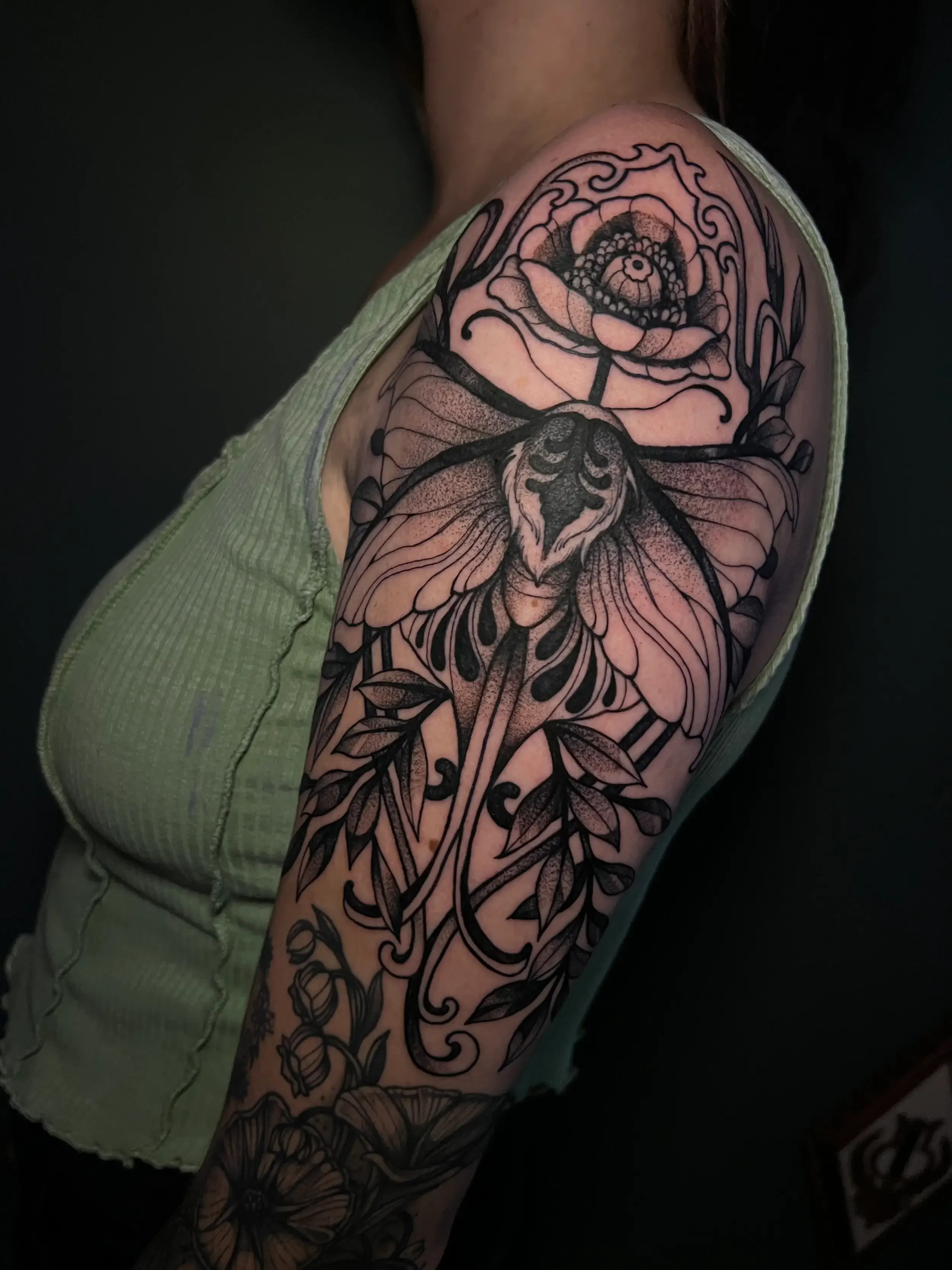 Custom neo-trad blackwork tattoo on person's upper arm featuring a moth and lotus flower.  Done by female tattoo artist Dana Carlson in Virginia.