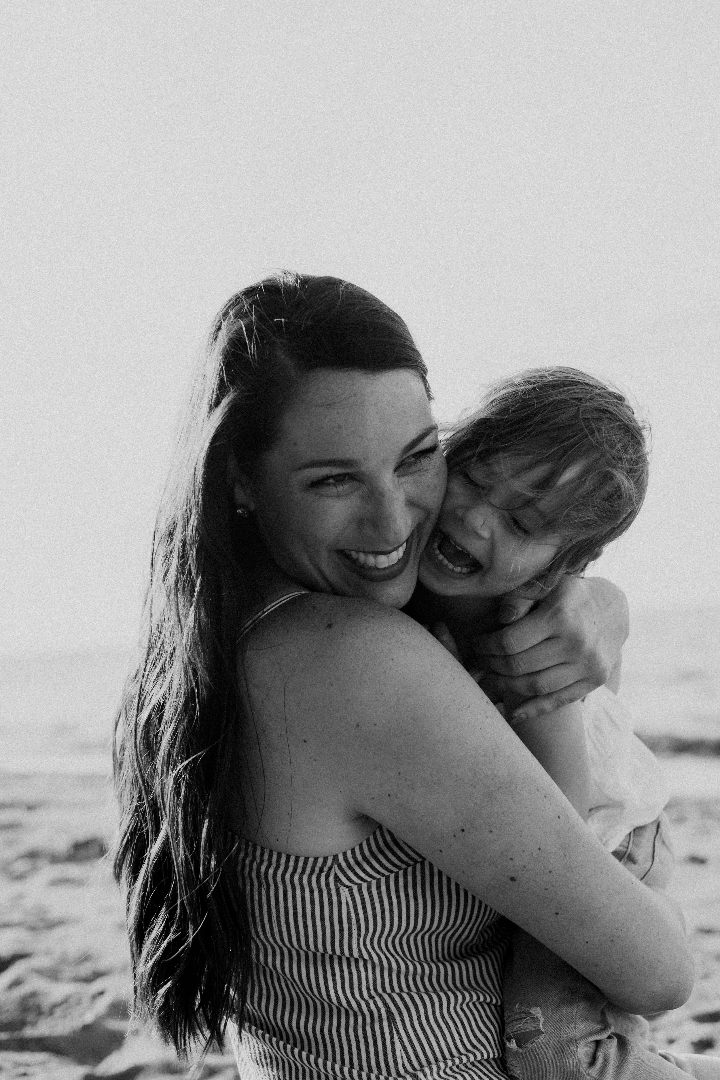 A black-and-white photo of a woman and a young child smiling and hugging on a Old Woman's Creek Beach in huron ohio