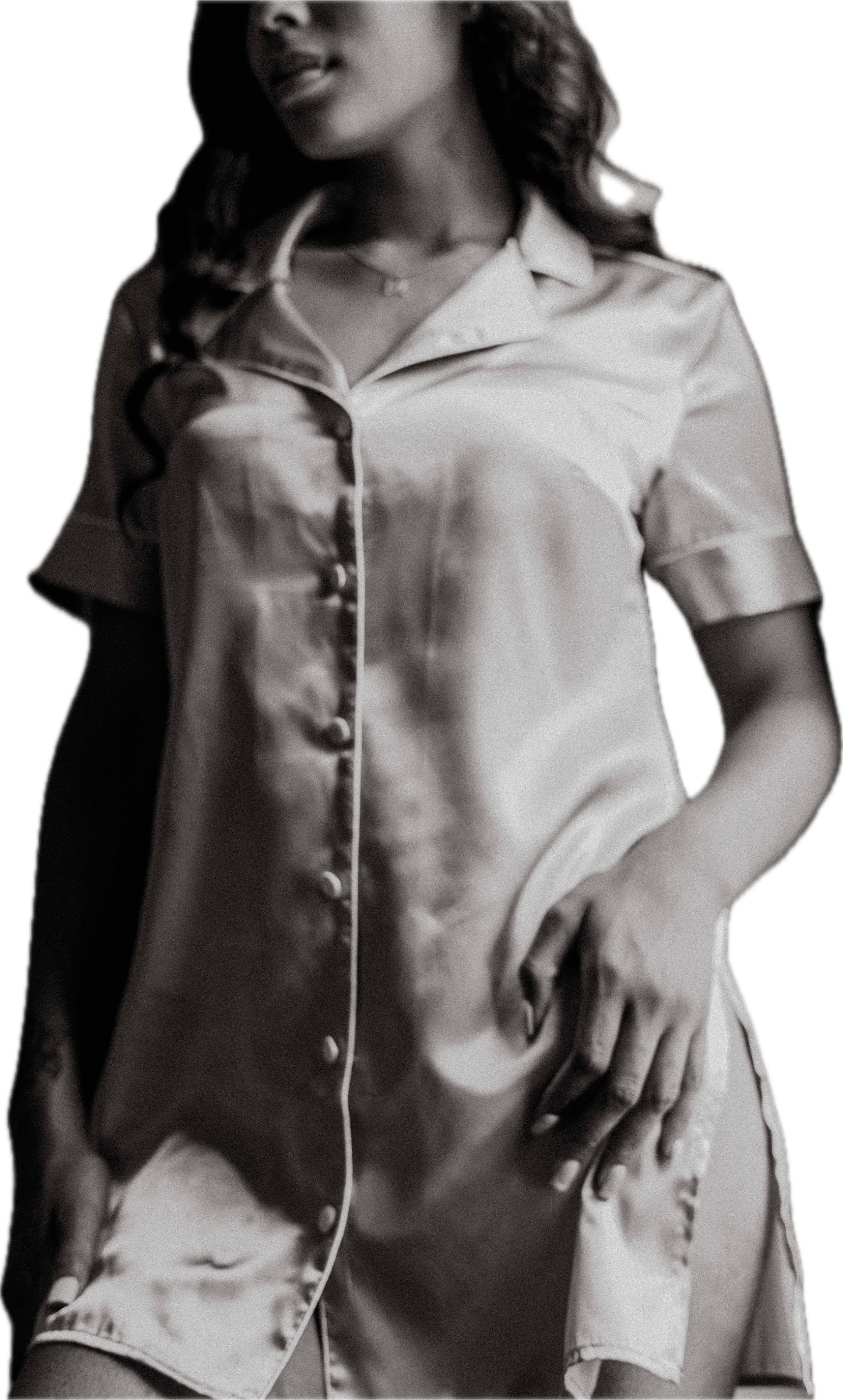 Black and white photo of a woman in satin pajamas with her hand on her hip for a boudoir photography shoot