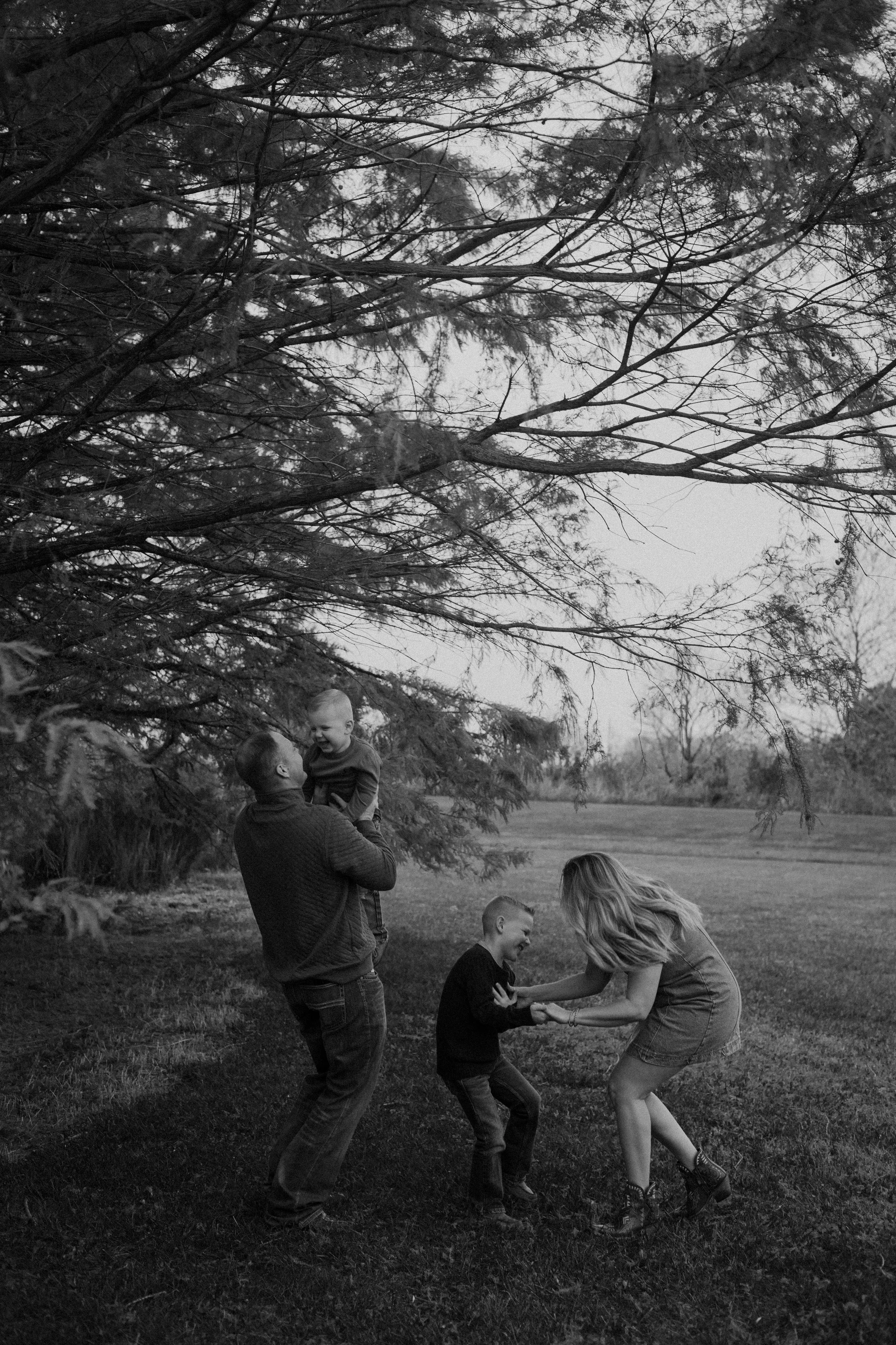 A family playing outdoors under a large tree on a grassy field in black and white at BGSU Huron Ohio