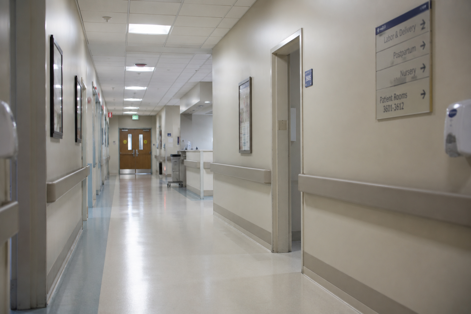 Quiet hospital labor and delivery hallway with soft overhead lighting and empty corridors, representing the emotional experience of navigating birth without continuous support.