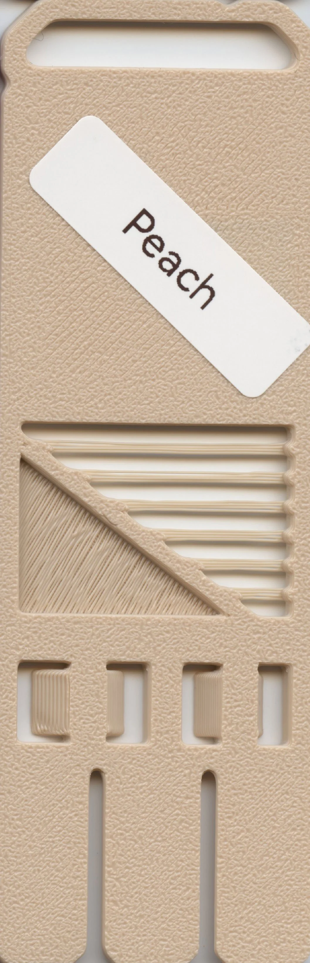 A beige plastic object with a white label reading 'Peach' and textured grooves.