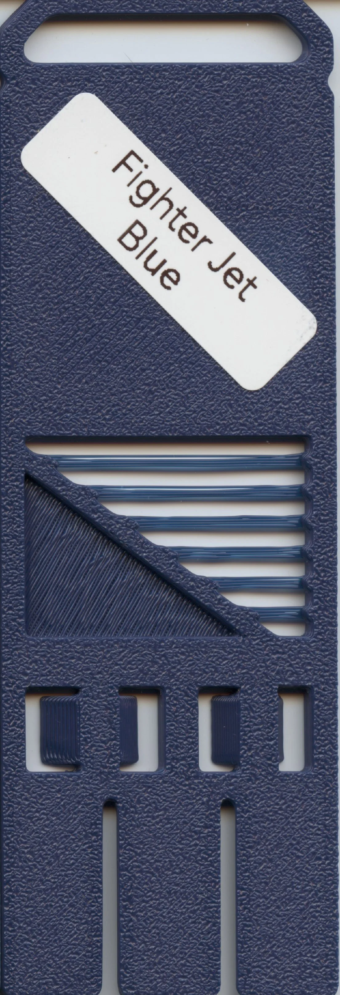 Close-up of a blue plastic fishing tackle box with a white label that reads 'Fighter Jet Blue' angled on the top surface.