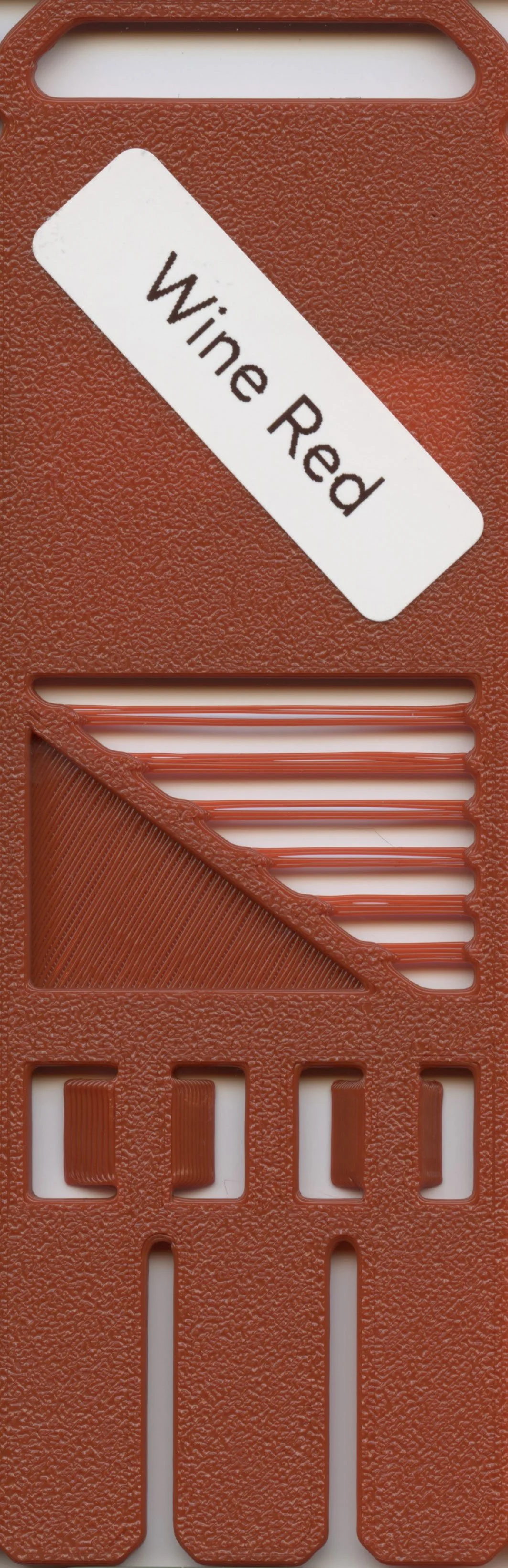 A textured brown plastic device with horizontal slots and a diagonal white label that reads 'Wine Red'.