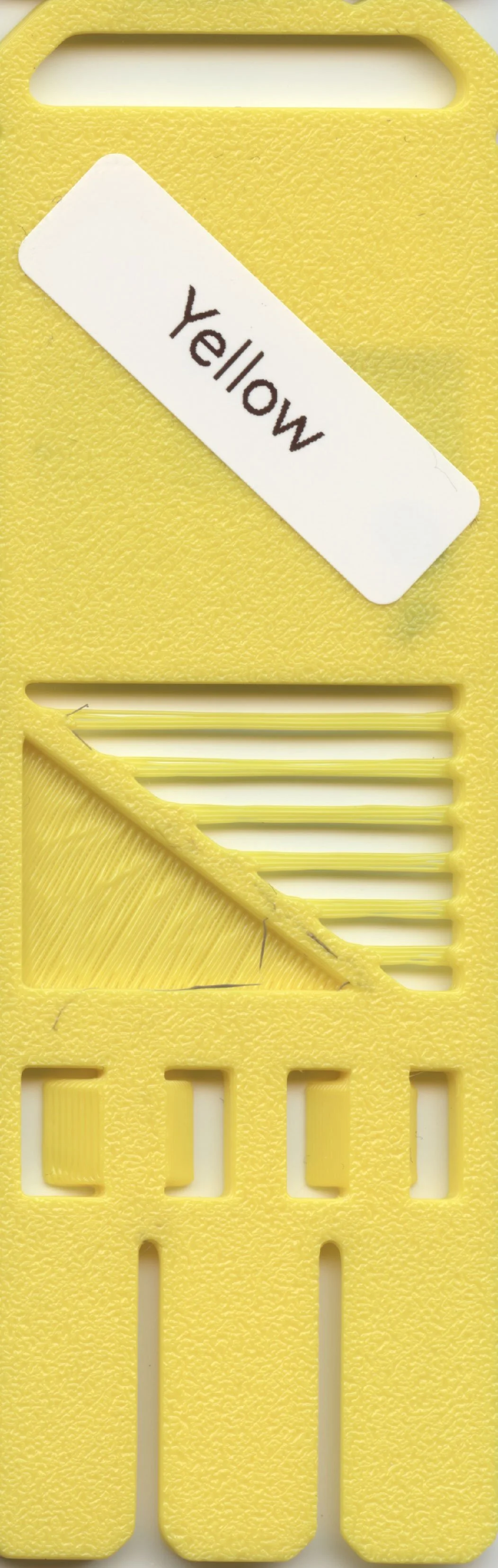 Yellow plastic Swiss Army knife handle with a white sticker labeled 'Yellow' and a cut-out section with stripped yellow thread or label inside.