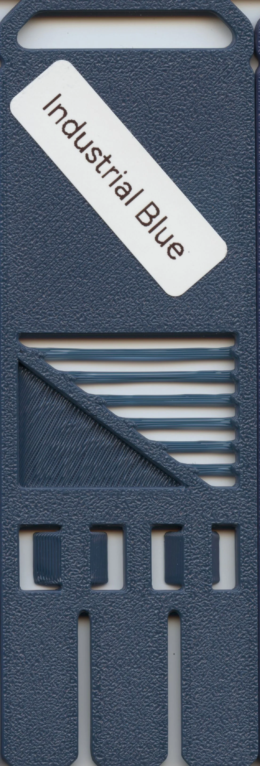 Close-up of a plastic sample or filter labeled 'Industrial Blue' with various textured and patterned sections.