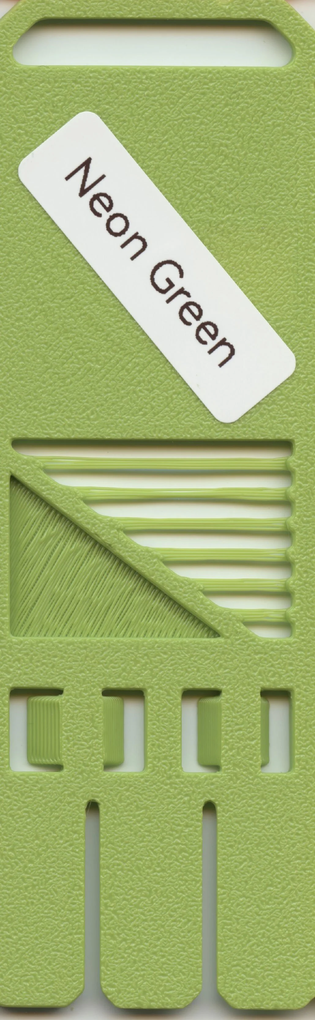 Close-up of a green plastic slotted tool with a label that reads 'Neon Green'.