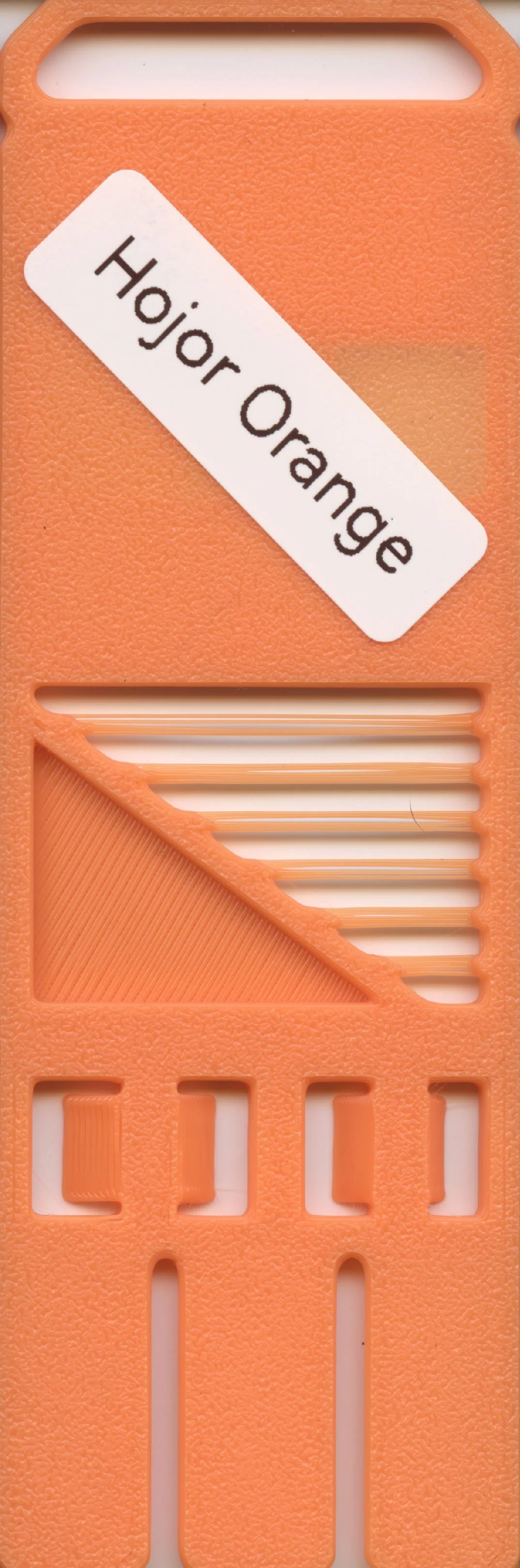Orange plastic device with the label 'Hojar Orange' and various cutouts, including a diagonal section showing a textured surface.