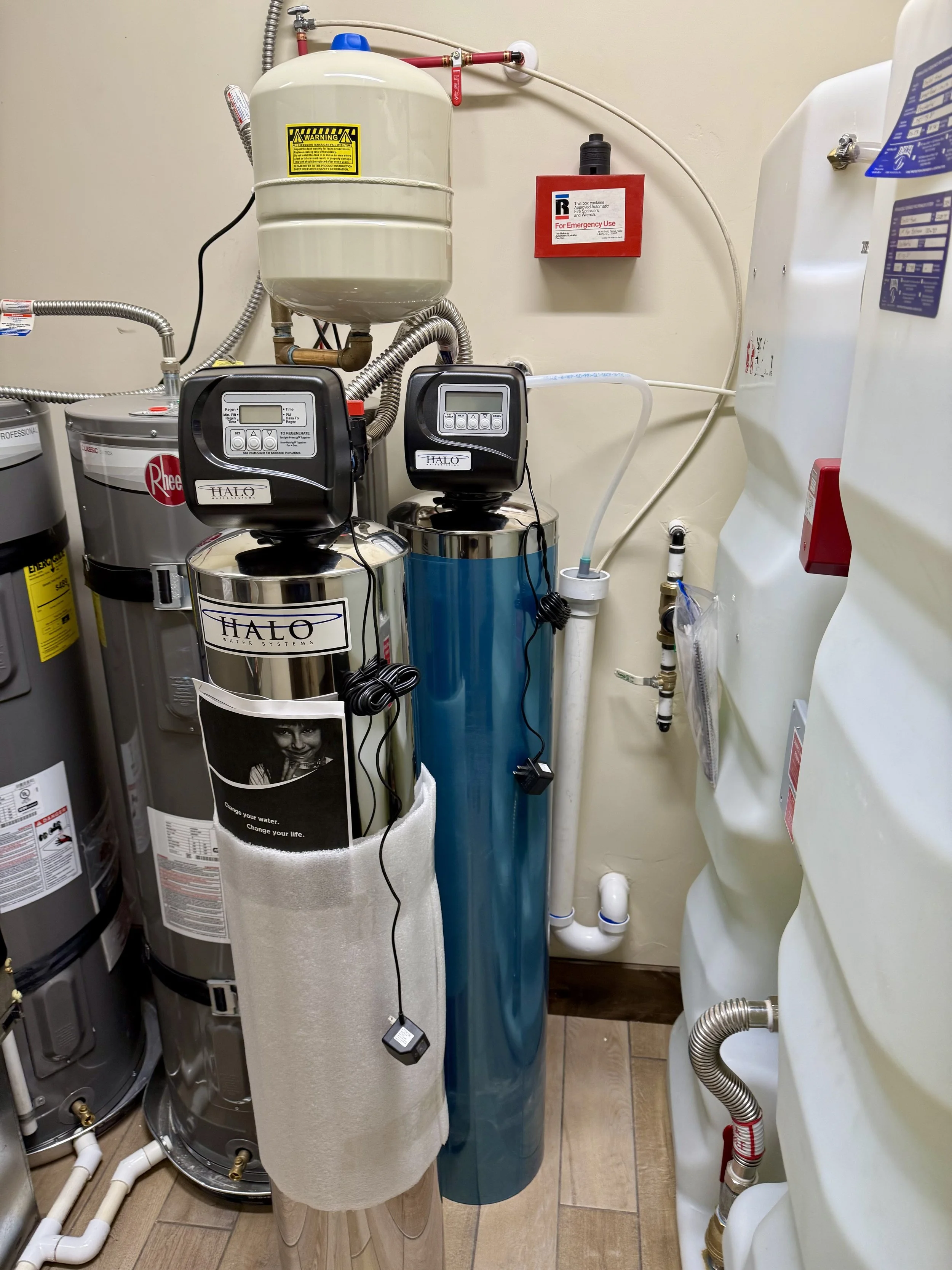 Water filter system installed in a laundry room with pipes, a furnace, and a water heater visible.