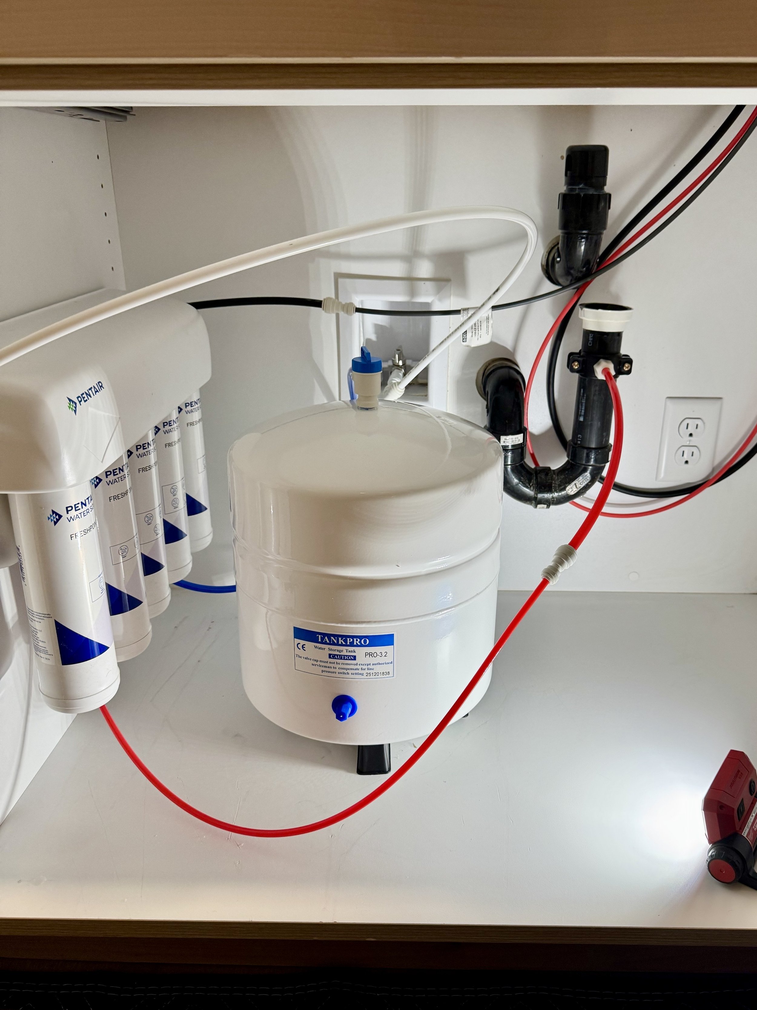Pentair Reverse Osmosis filtration system and storage tank installed beneath a countertop by Artisan Plumbing.