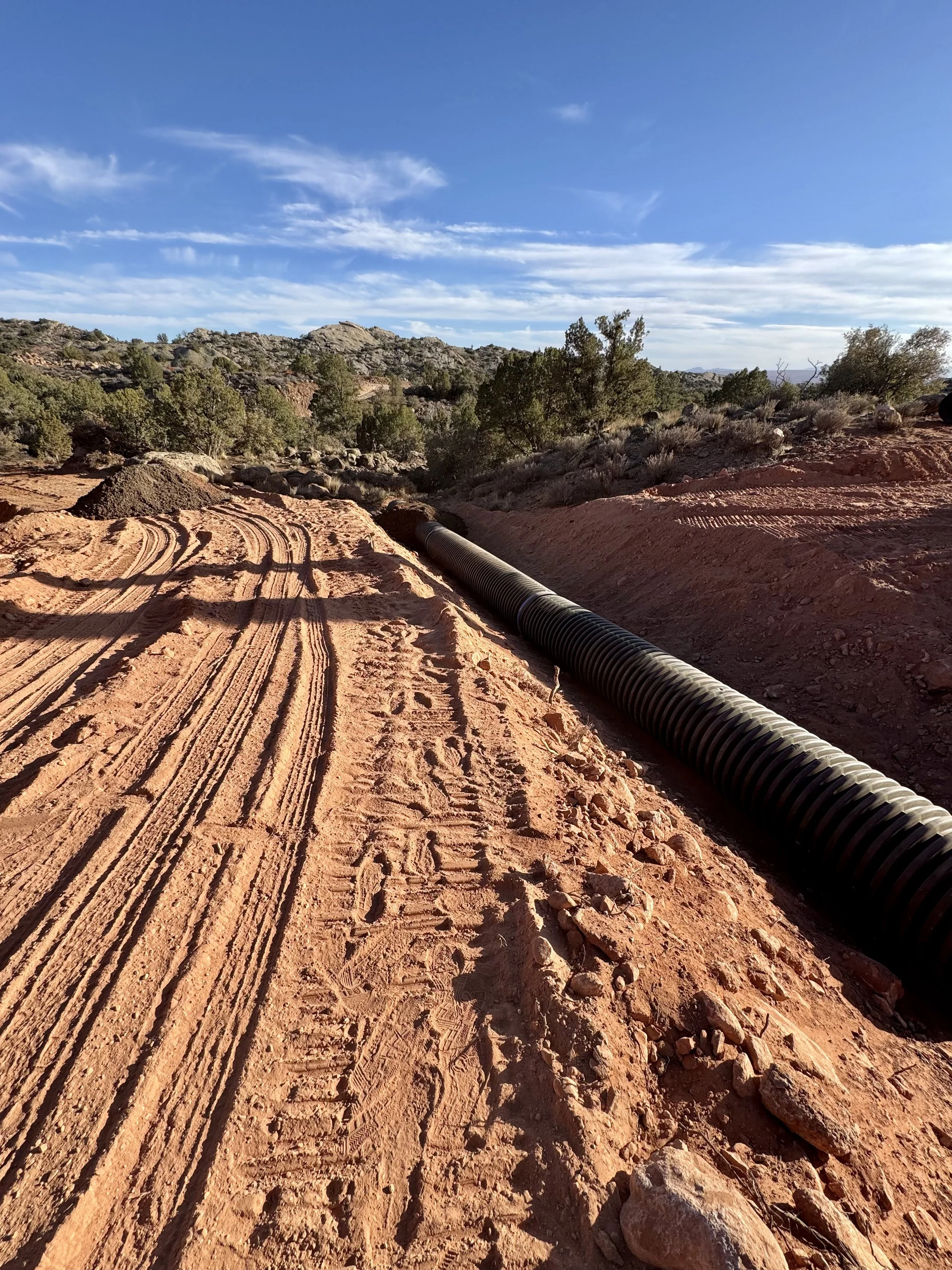 Underground utility pipe installation in excavated red soil on a Southern Utah property