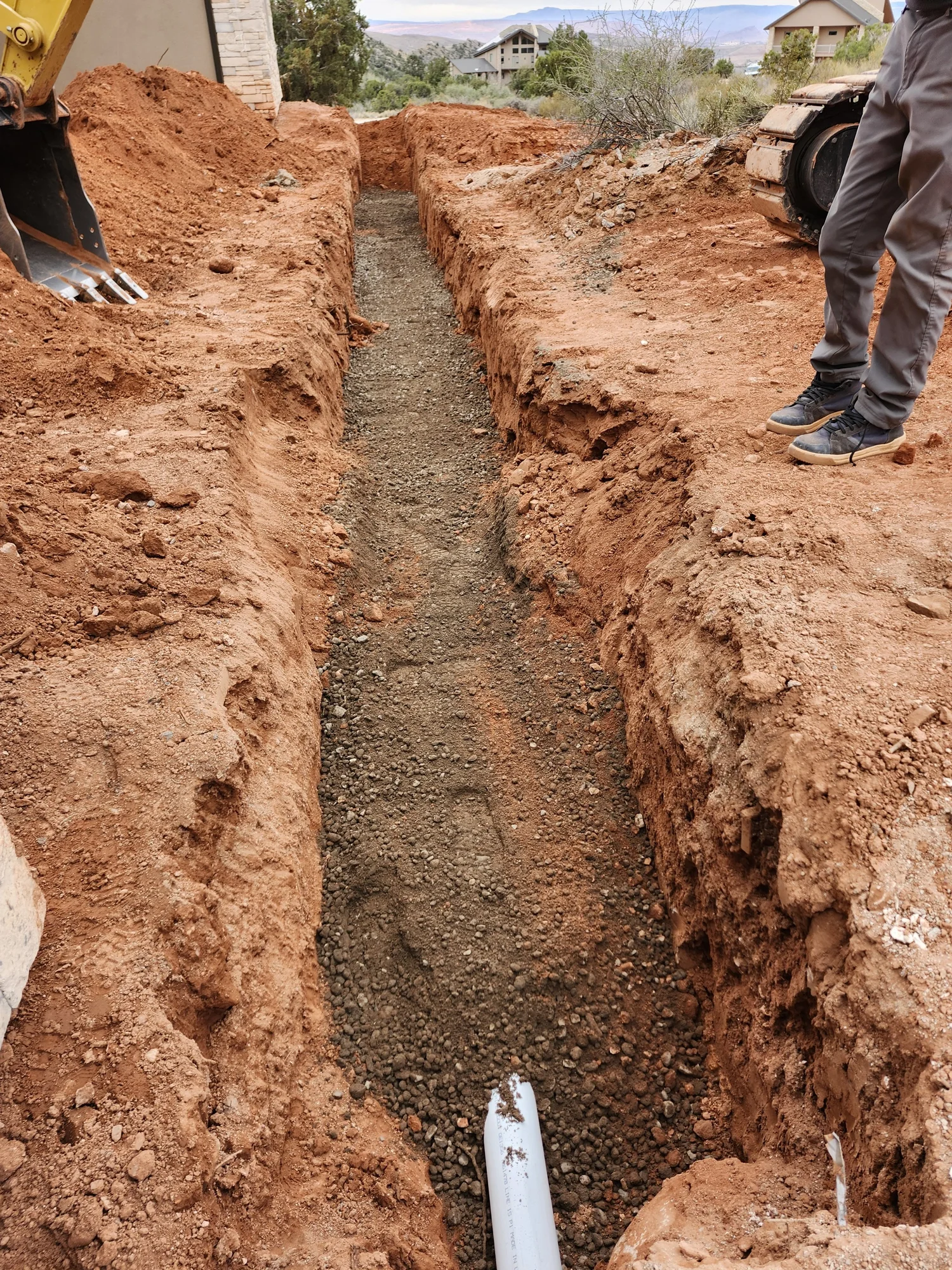 Excavated utility trench and installed underground white pipe at an Artisan Group project