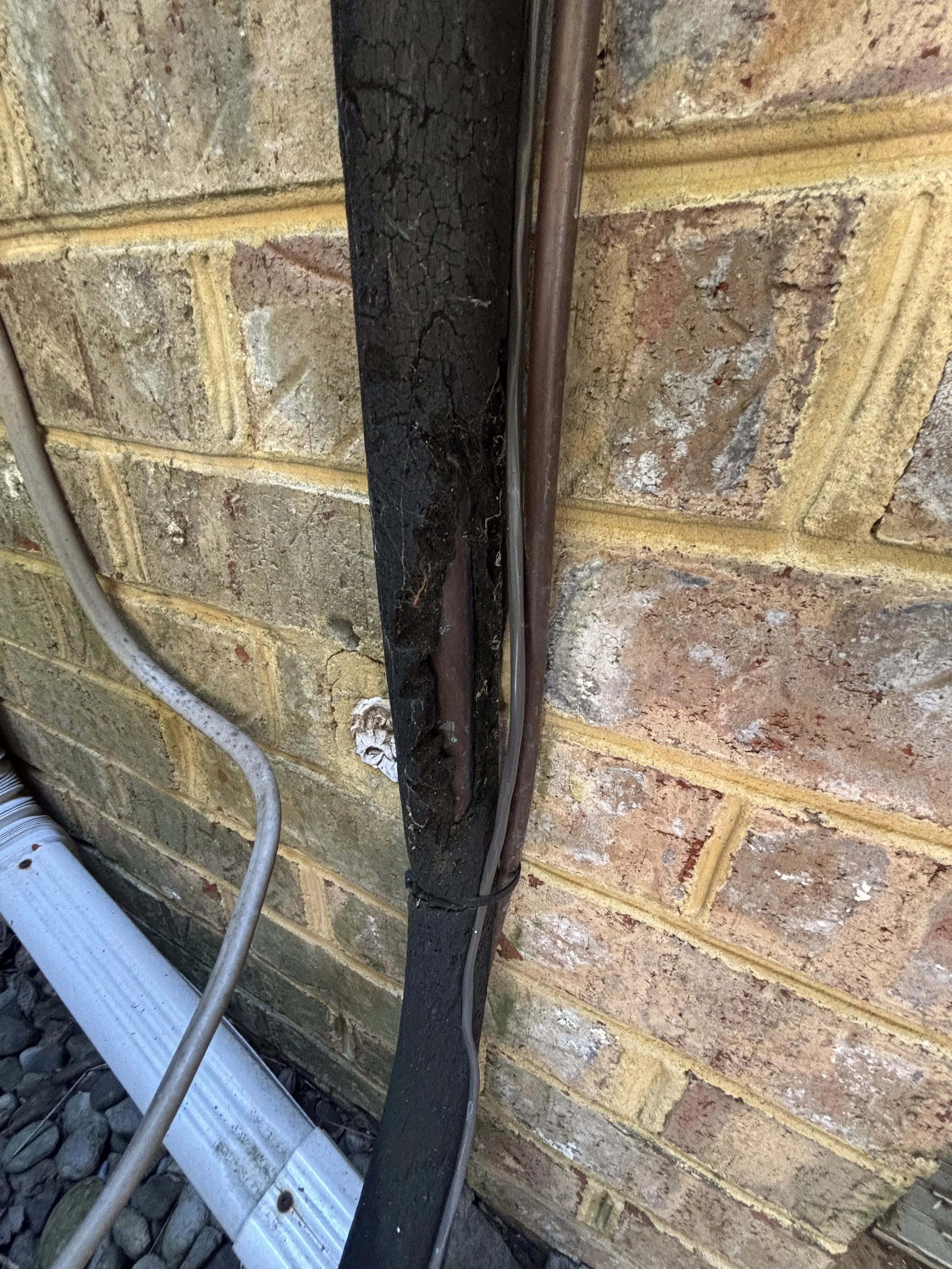 Damaged insulation on exterior refrigerant line set at condenser.