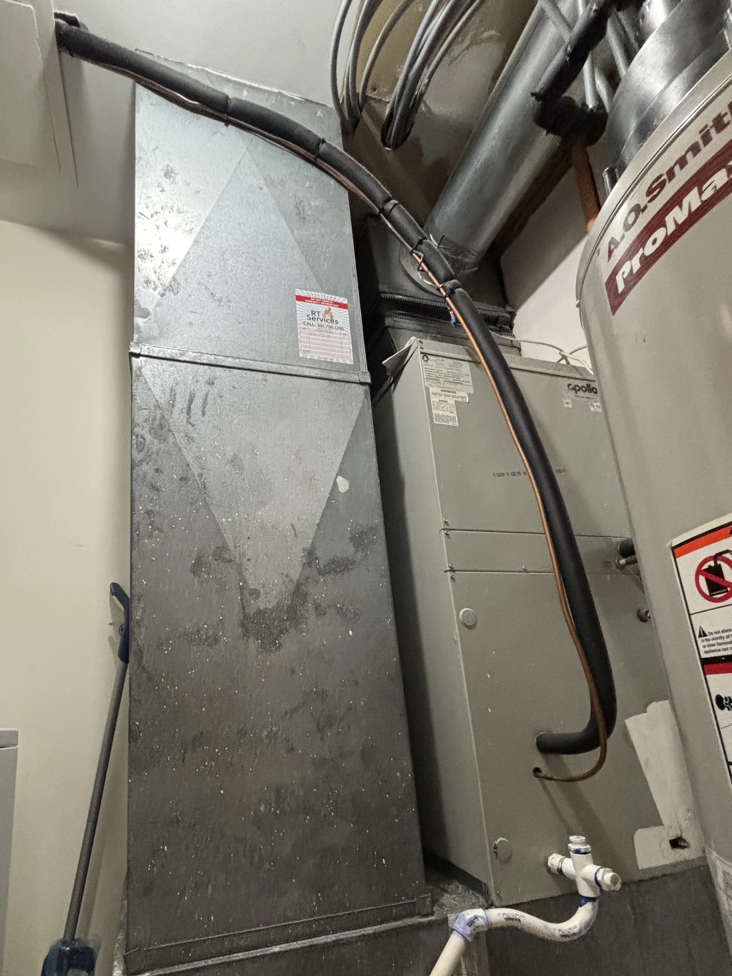 Interior air handler unit with refrigerant lines entering from the ceiling, condensate drain line and cleanout visible below, and insulation around lines appearing intact