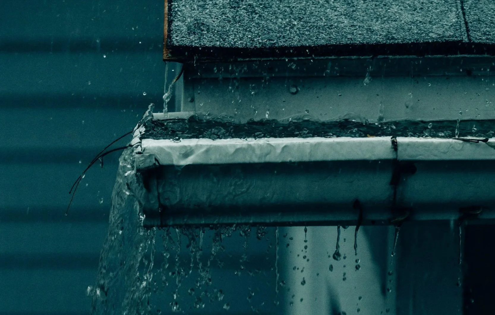 Gutter overflowing during a rain event, showing water spilling over the sides due to blockage or limited drainage capacity.