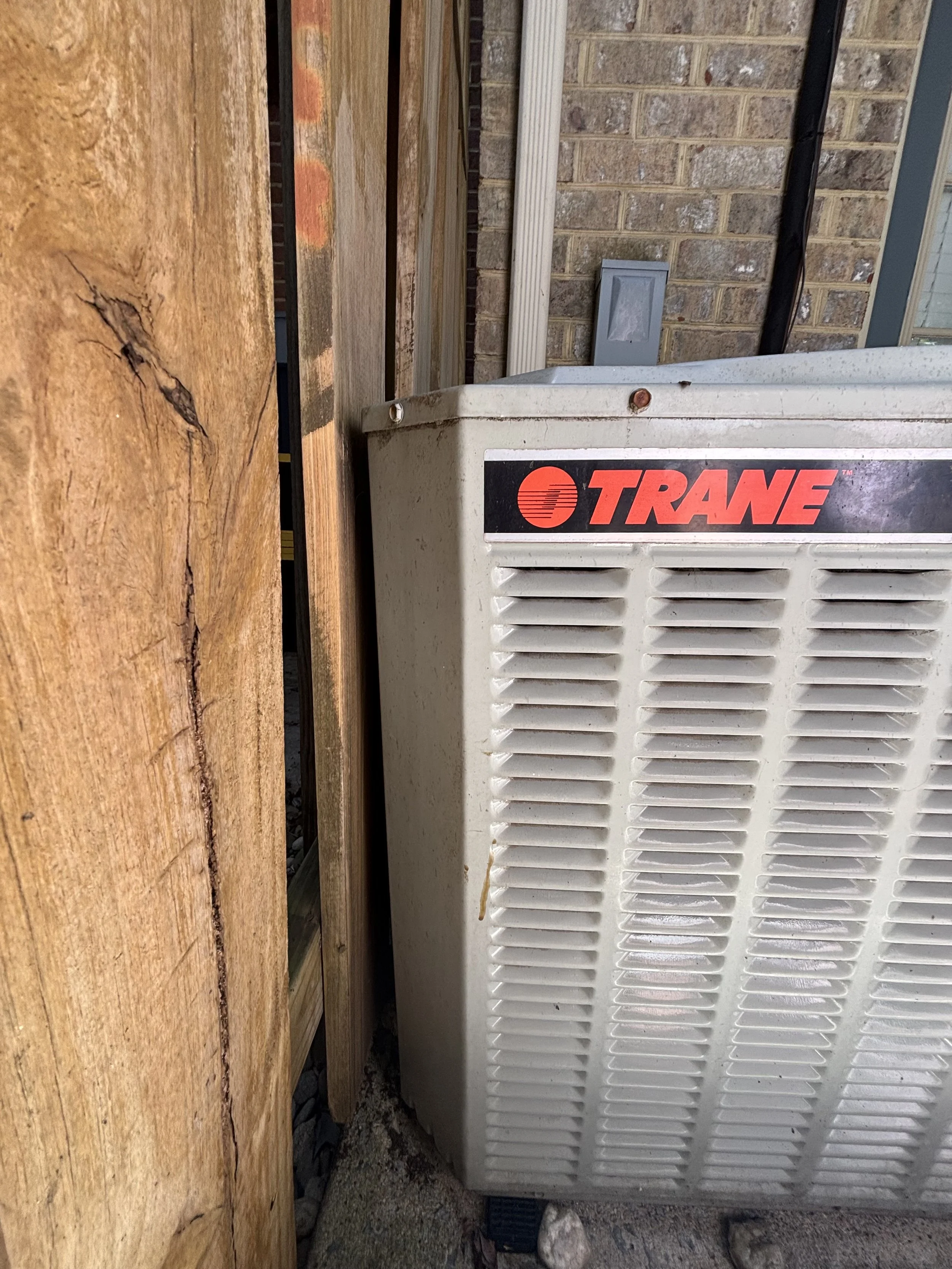 Outdoor Trane air conditioning condenser unit positioned close to a fence.