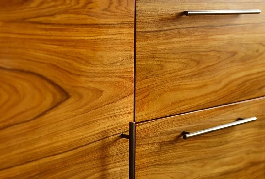 Close-up of wooden cabinet with sleek metal handles.