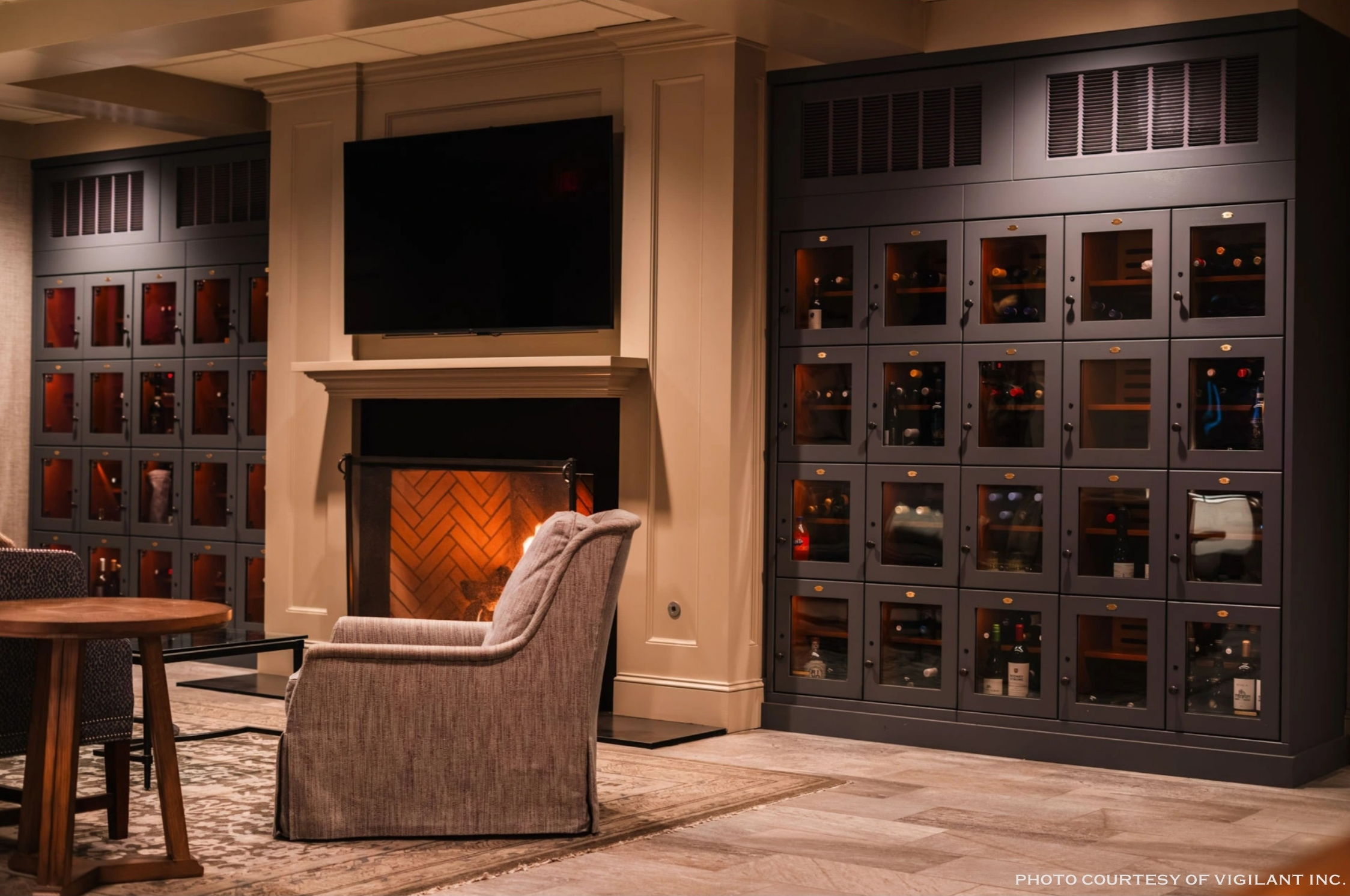 A cozy room with a fireplace, a flat-screen TV above the fireplace, and large wine storage cabinets on either side of the TV.