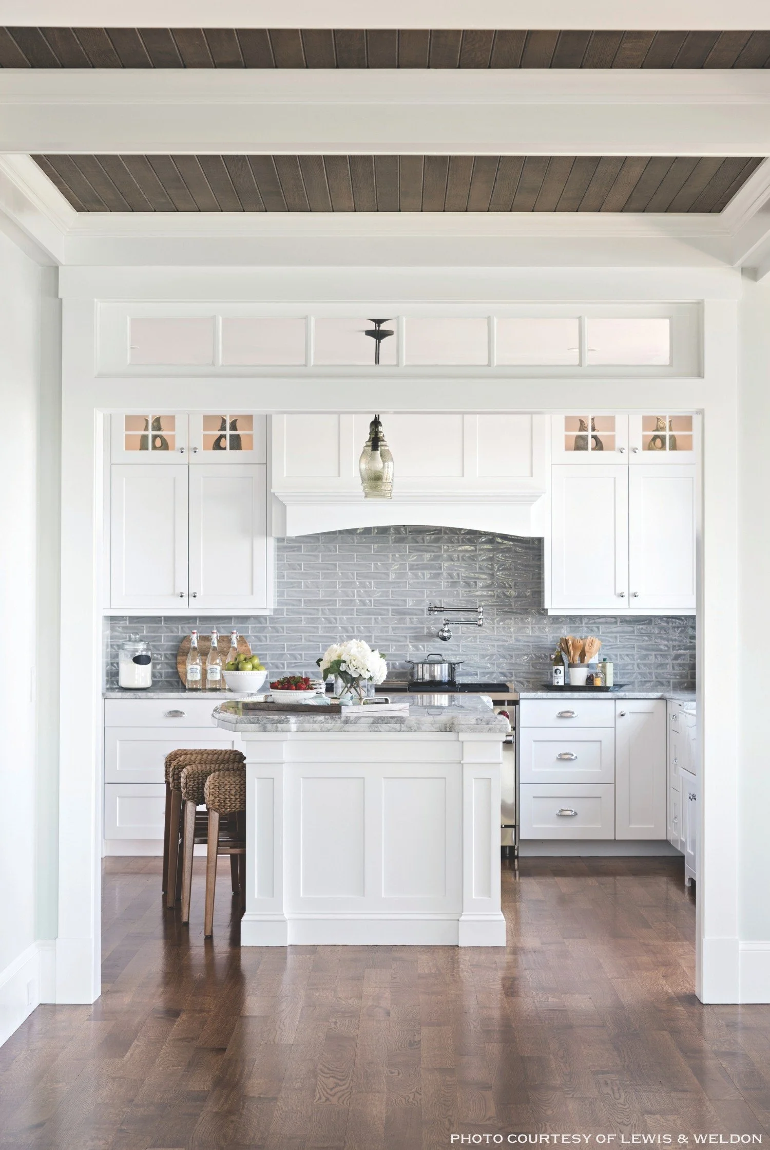 A modern white kitchen with a marble countertop island, and white cabinets