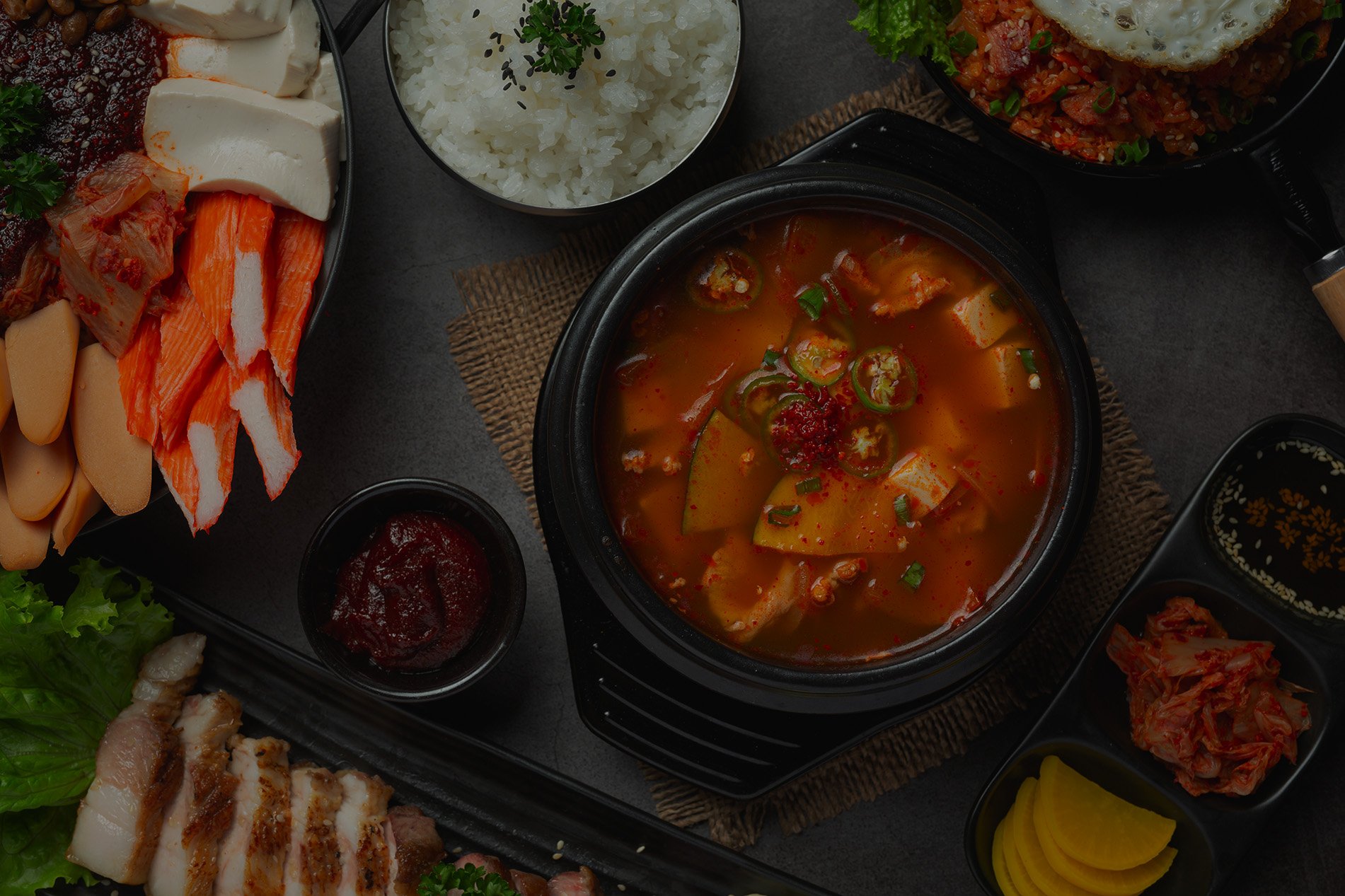 Close-up of traditional Korean spicy stew in a hot stone bowl surrounded by fresh side dishes at Korea BBQ & Sushi in Brentwood, TN.