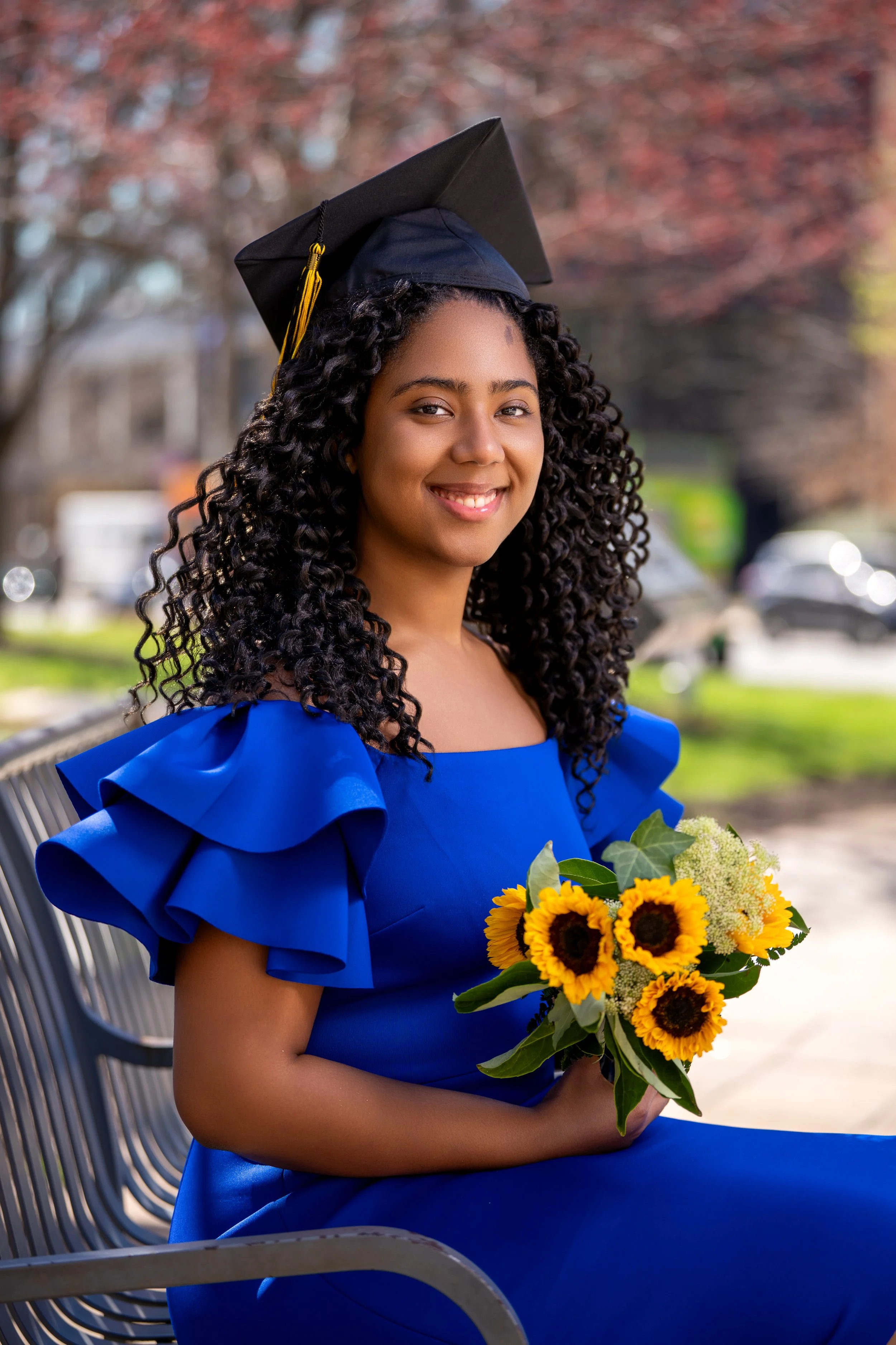 close up graduation portrait of smiling female graduate holding sunflowers in Philadelphia outdoor photoshoot
