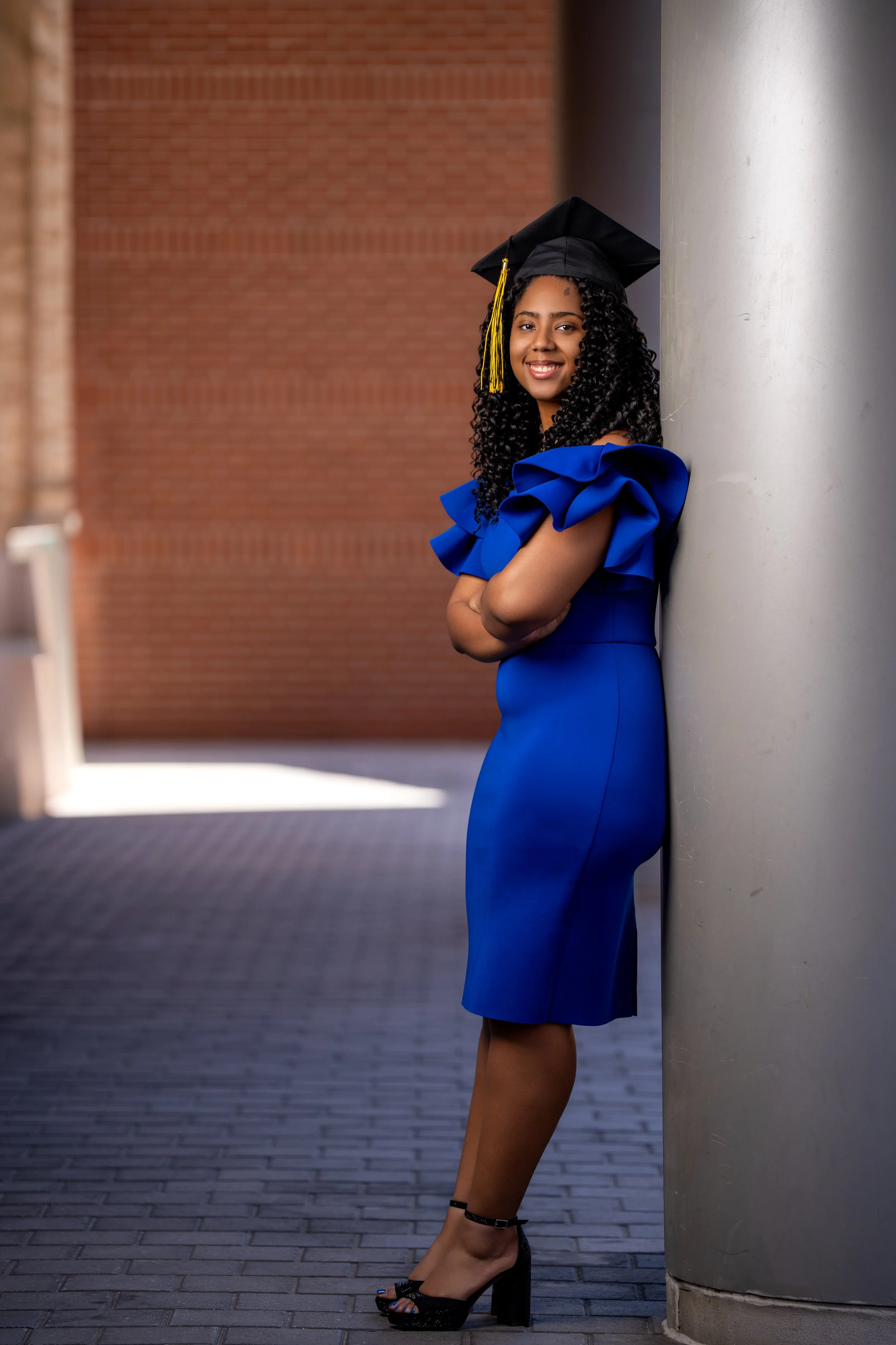 female graduate posing outdoors in blue dress and cap for professional graduation photos in Philadelphia