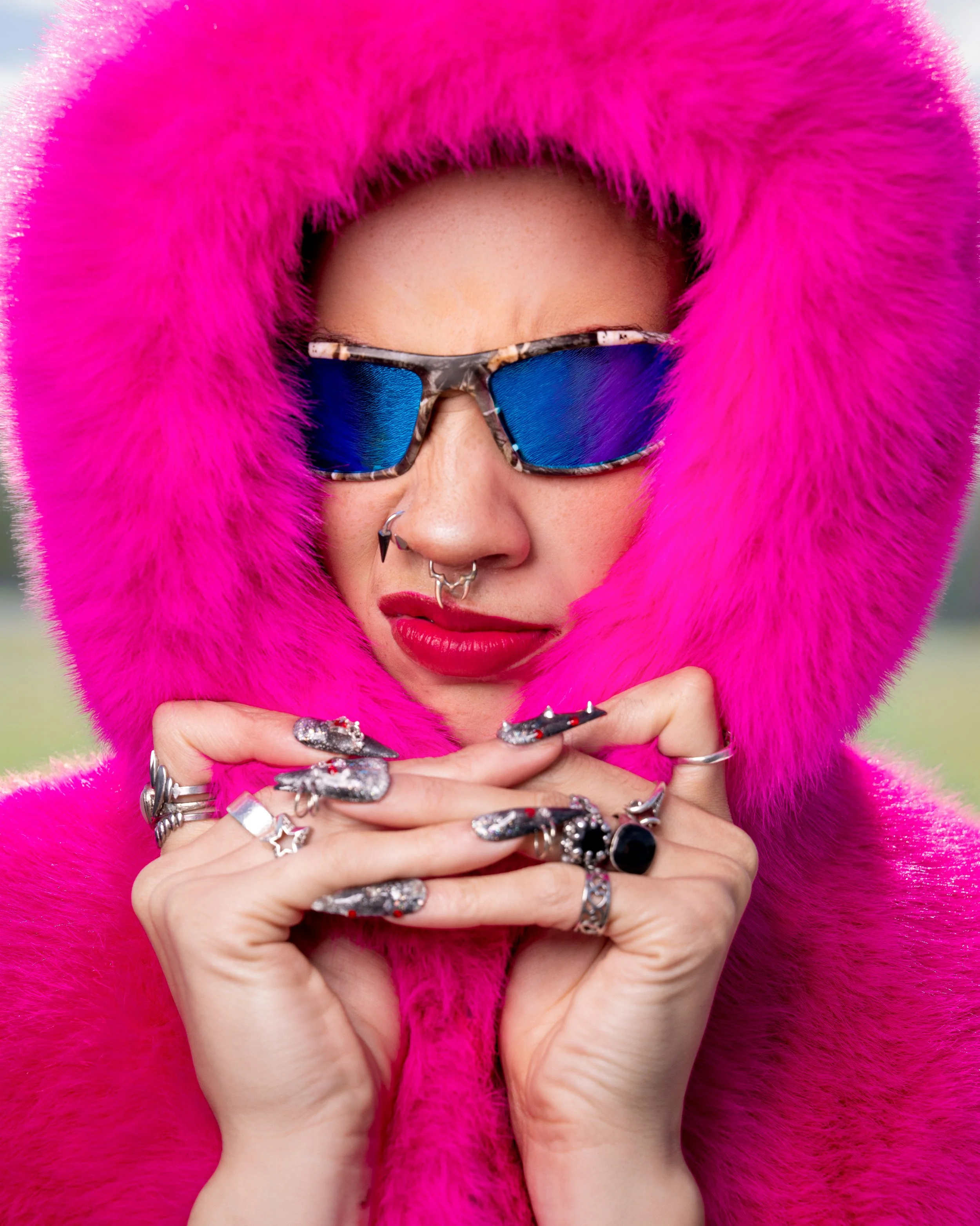 High-fashion beauty portrait featuring vibrant pink styling and bold blue sunglasses.