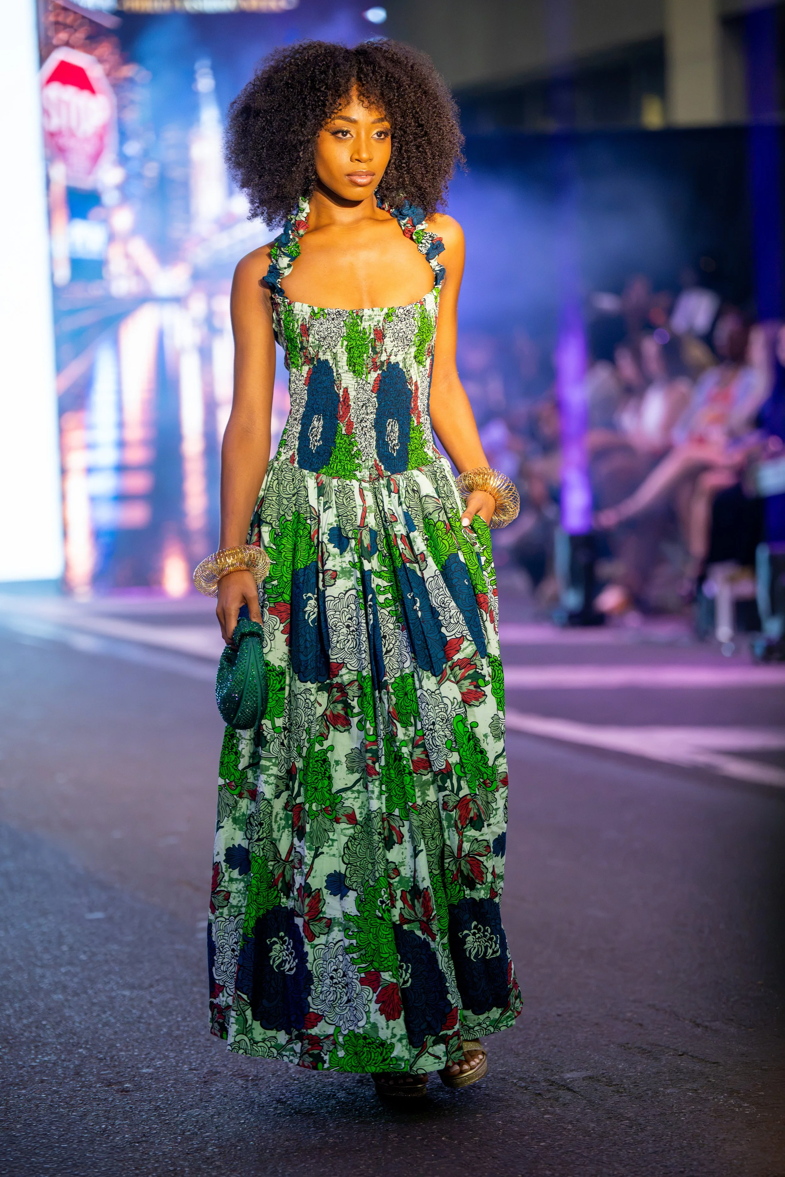 Model on the Philly Fashion Week runway wearing a floor-length green, blue, and white patterned gown with a fitted bodice and flowing silhouette.