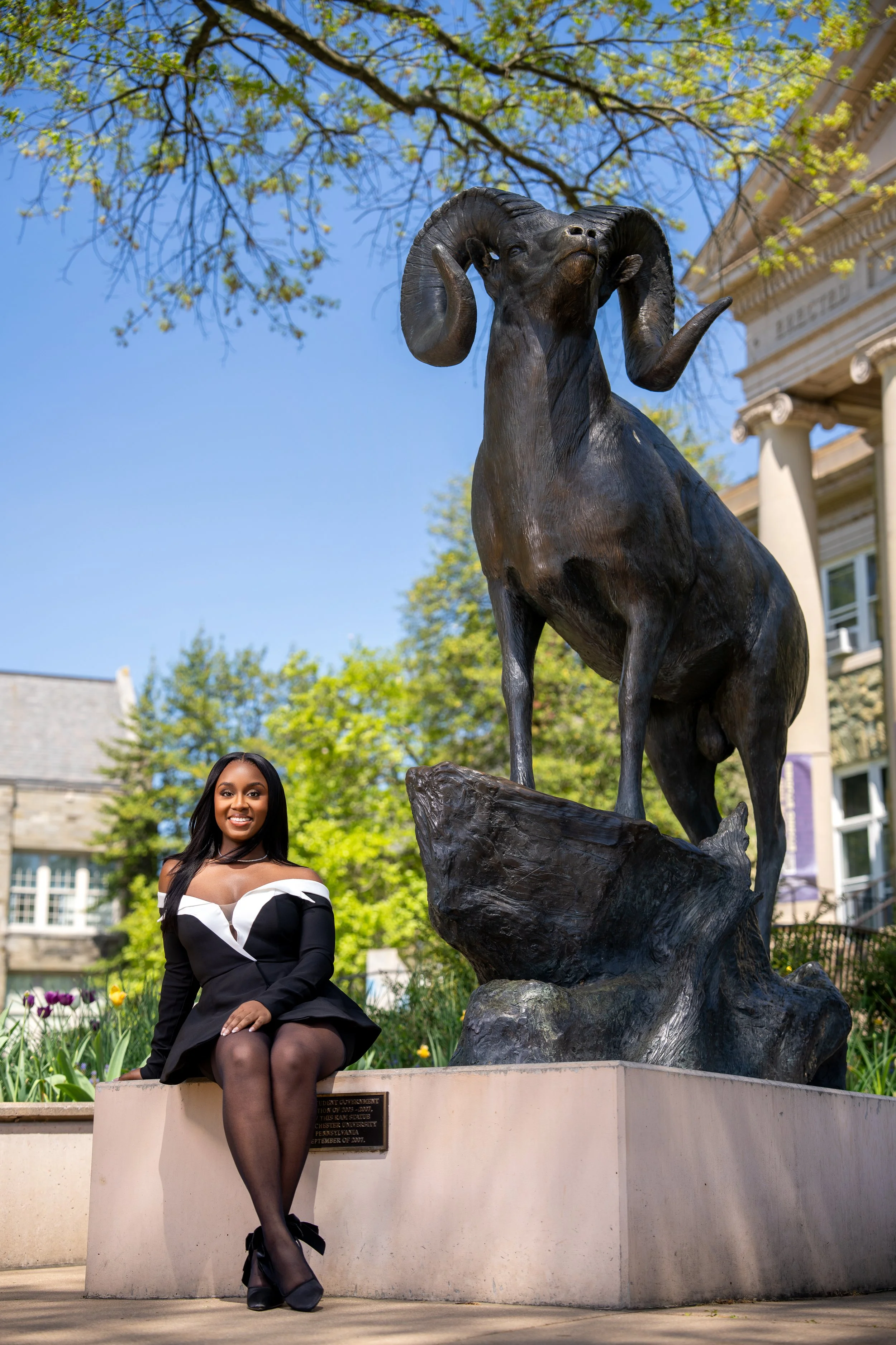 West Chester University graduation photoshoot with graduate posing outdoors on campus landmark